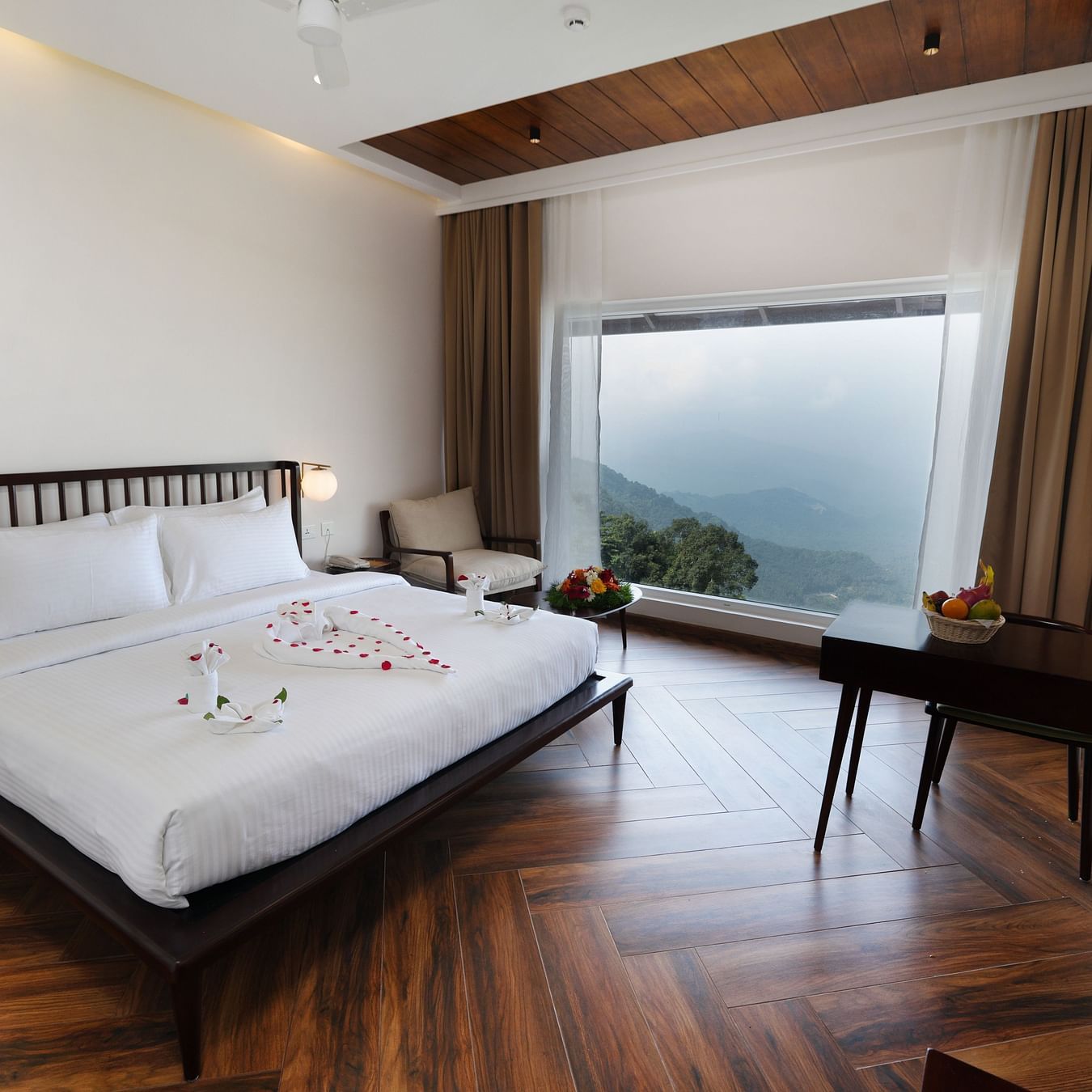 A bed in a room with a huge glass window | Misty Queen by Dimora, Kakkadampoyil