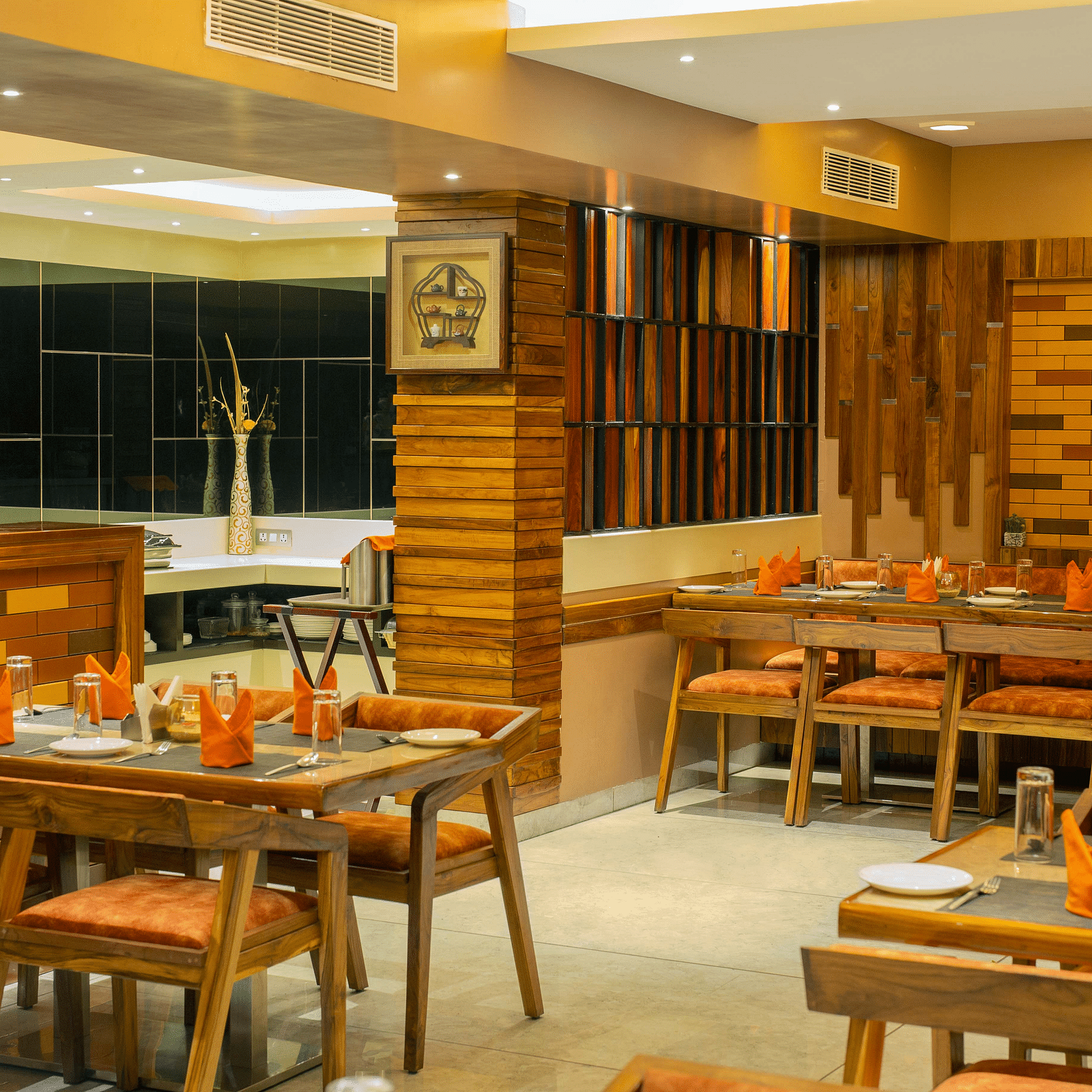 Image of the interiors of Honeycomb Restaurant at Coral Reef Hotel & Spa in Port Blair under warm lighting and walnut furniture 