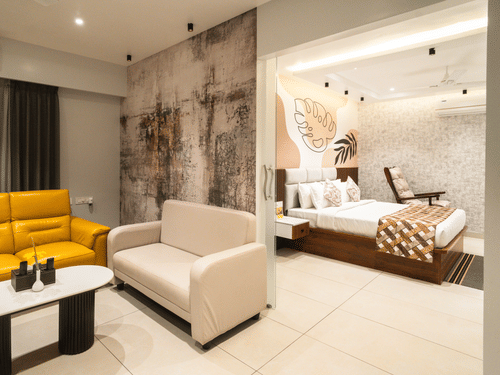 An image of a room with a plush bed in the bedroom and sofas placed around a coffee table in the living room - MGM Whispering Meadows