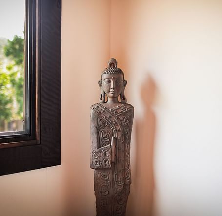 A serene corner with a rustic statue adding a peaceful touch in the massage room at Brewery Gulch Inn & Spa