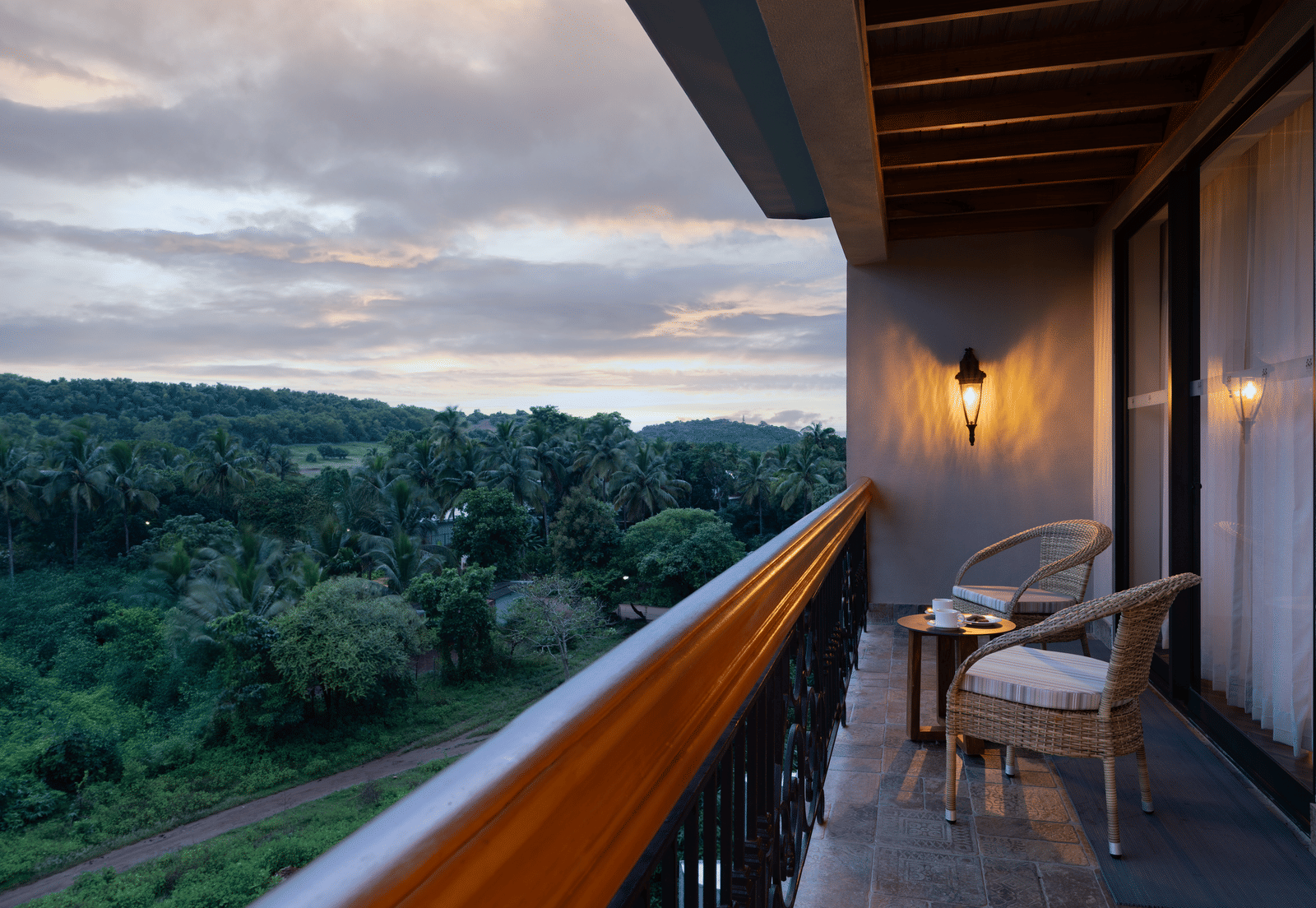 The balcony at the Evren Suite overlooking at the lush green forests with a cloudy evening sky in the background at The Evren, Vagator.