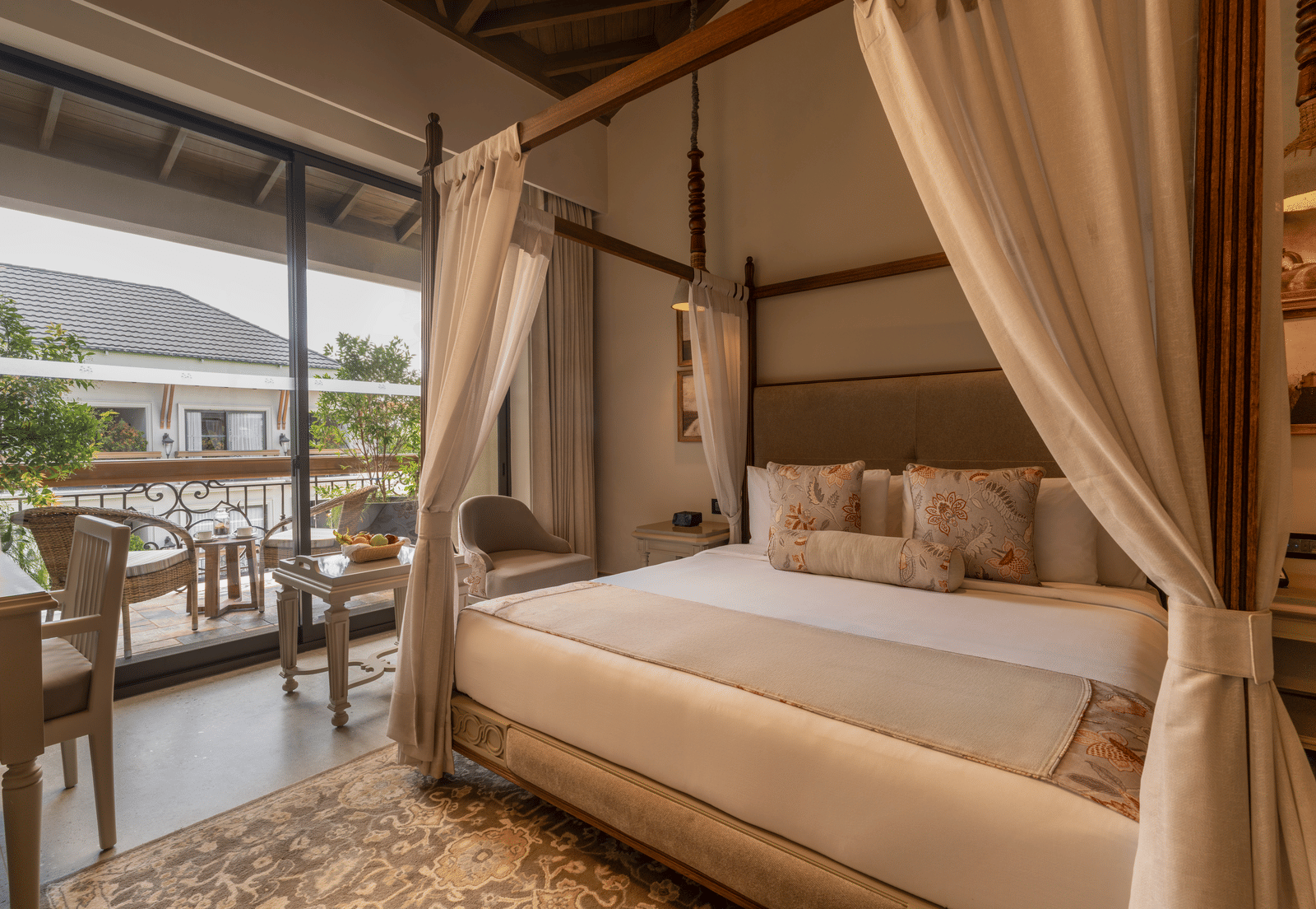 A plush double bed in the Premium Room at The Evren, Vagator, with a balcony beside it featuring a sit-out area.