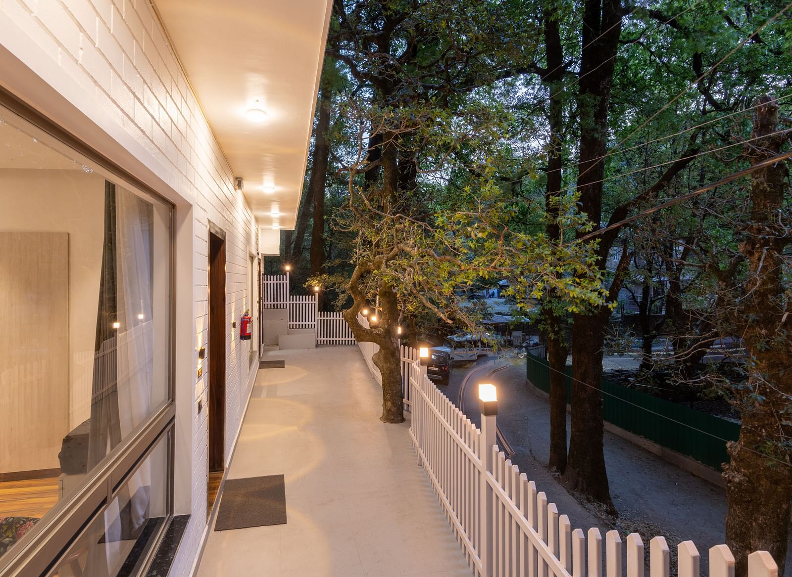 The common balcony area near the rooms at DLS The Emerald, Nainital surrounded by trees and greenery