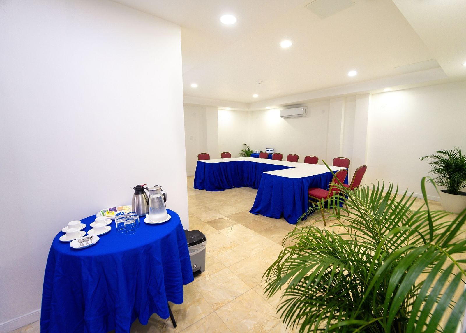 A cosy conference room setup with deep blue tablecloths and lush plants - Hotel 39, Jamaica (Montego Bay)