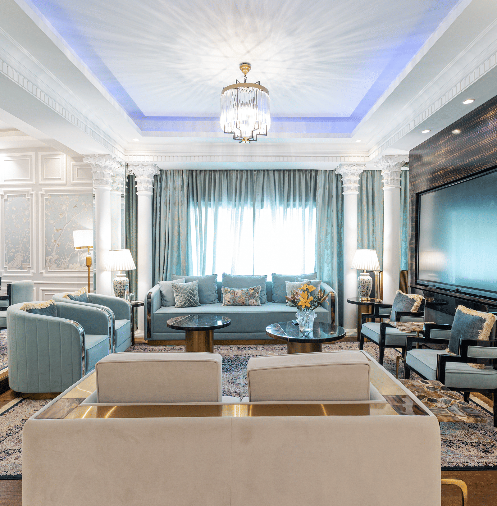 Claridges Suite at The Claridges New Delhi, featuring a cosy sofa beneath a chandelier and surrounded by elegant ambient lighting