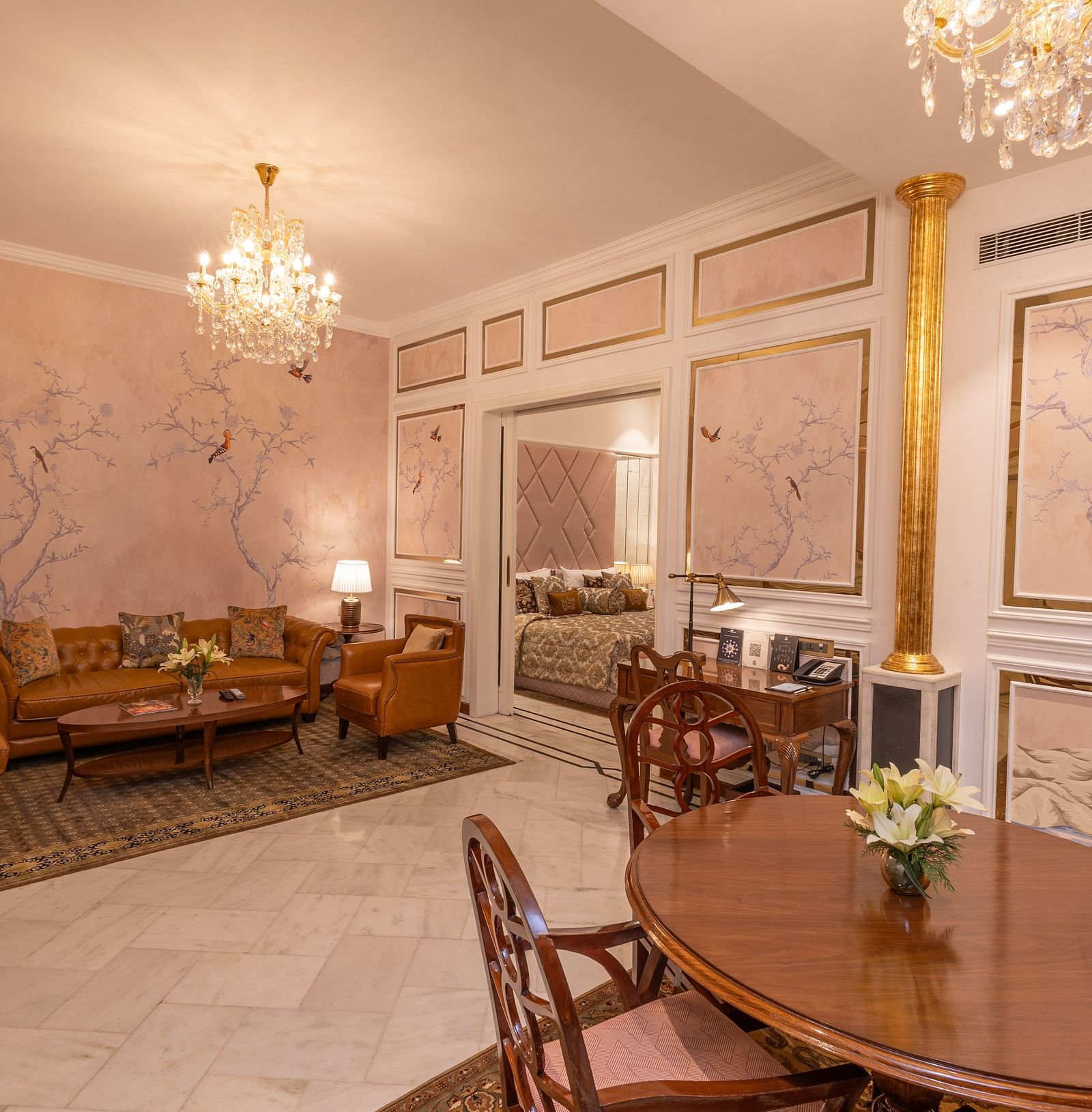 Luxury Suite at The Claridges New Delhi, featuring a large corner sofa, an elegant dining table, and a chandelier hanging overhead