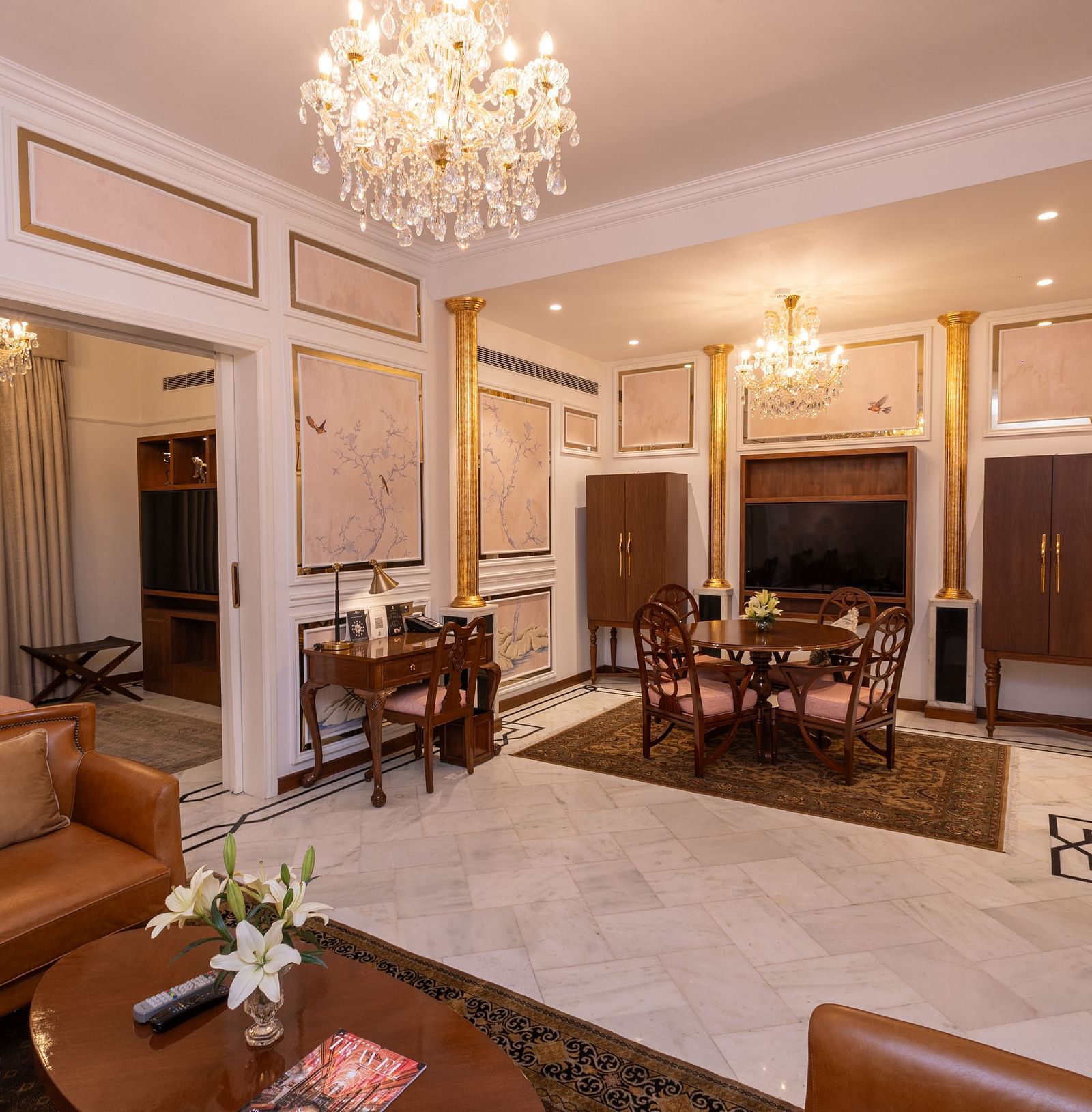 Luxury Suite at The Claridges New Delhi, featuring a spacious room with a corner sofa and a chandelier