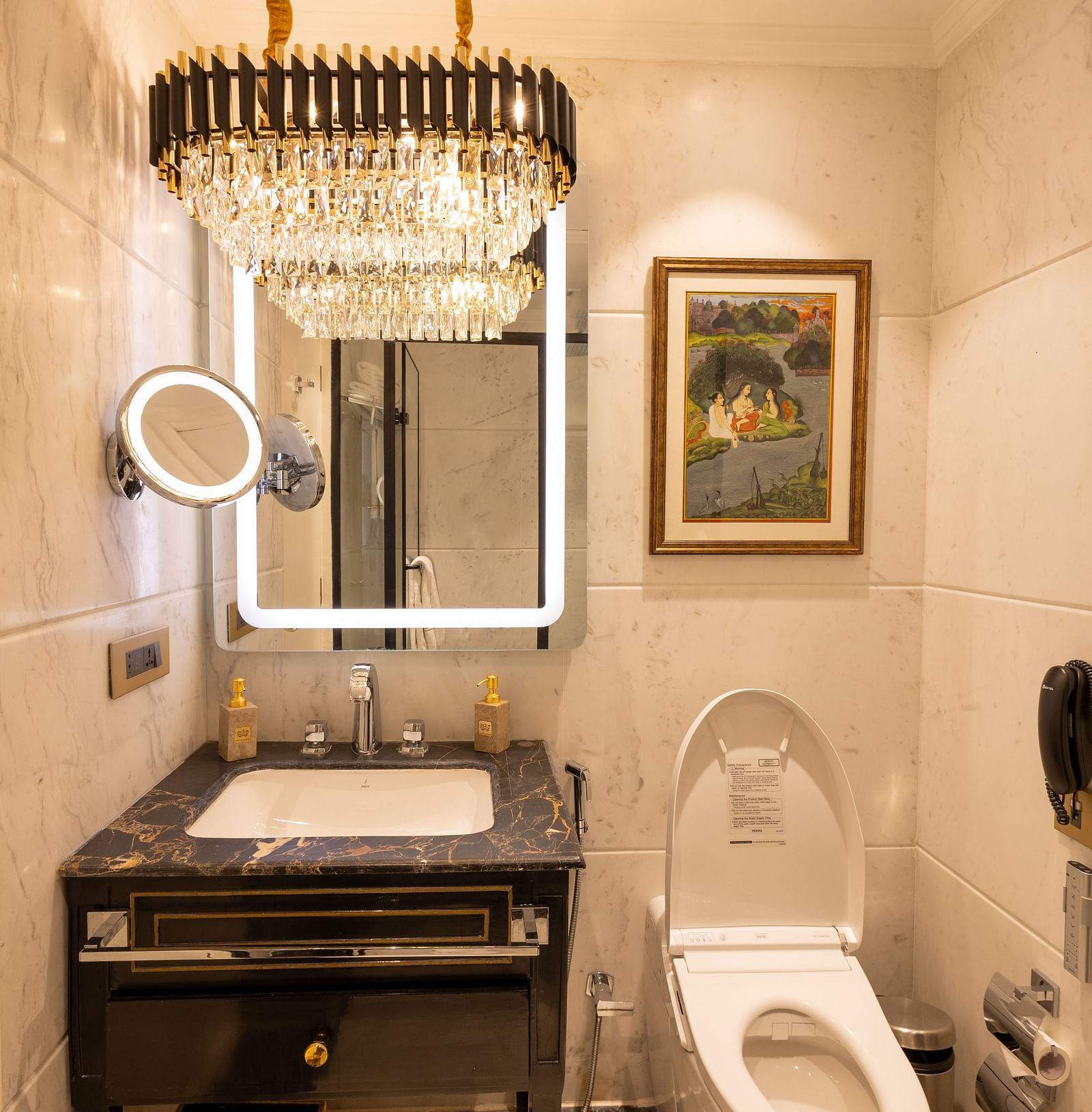 Luxury Suite washroom at The Claridges New Delhi, featuring a stylish sink, wall-mounted mirror, and a chandelier
