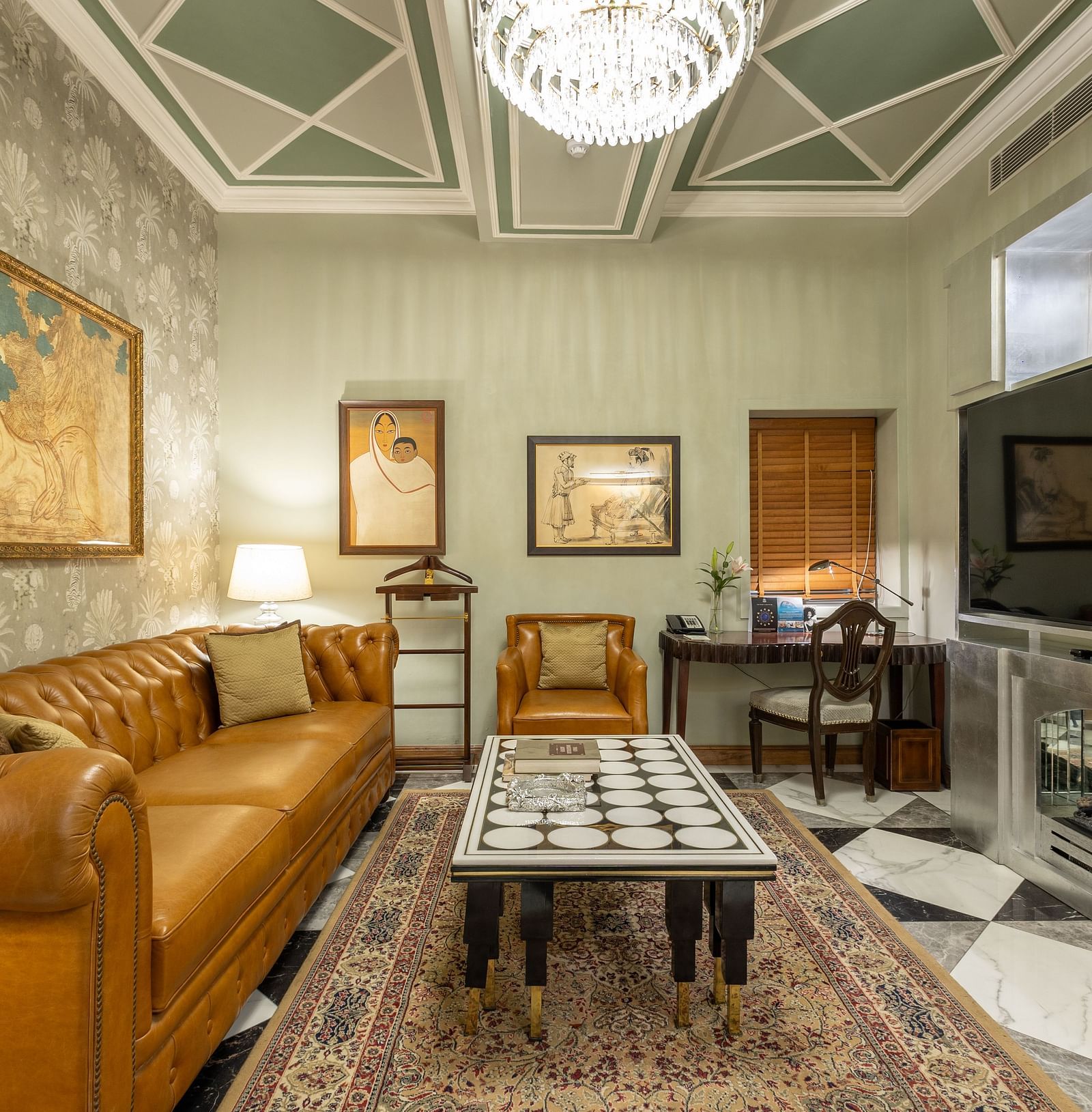 Luxury Suite with Whirlpool at The Claridges New Delhi, featuring a spacious cosy sofa, a table in front, and a chandelier hanging overhead