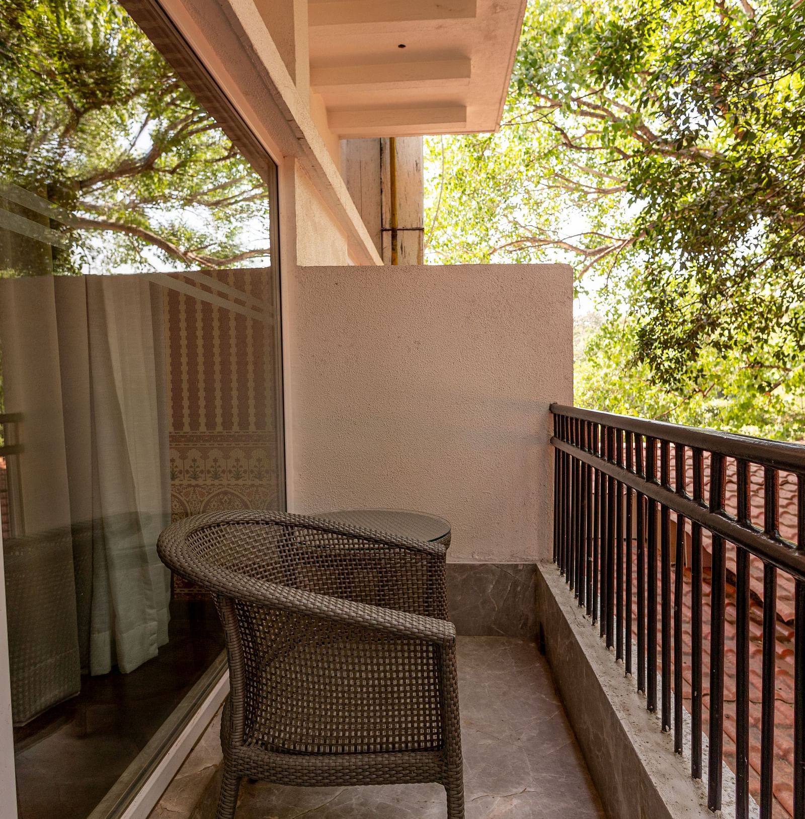 Balcony of the Luxury Twin Bed Room with Balcony at The Claridges New Delhi, featuring a comfortable chair and a glass door