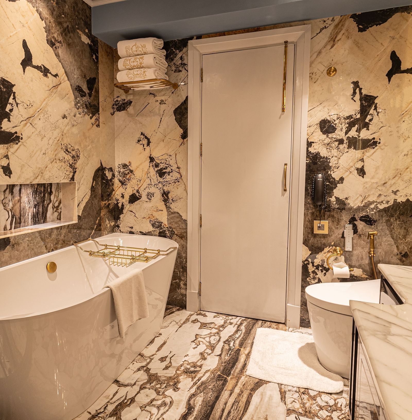 image of a luxurious bathroom with a bathtub at one side with white and black marble on the walls at the heritage parlour suite - The Claridges New Delhi