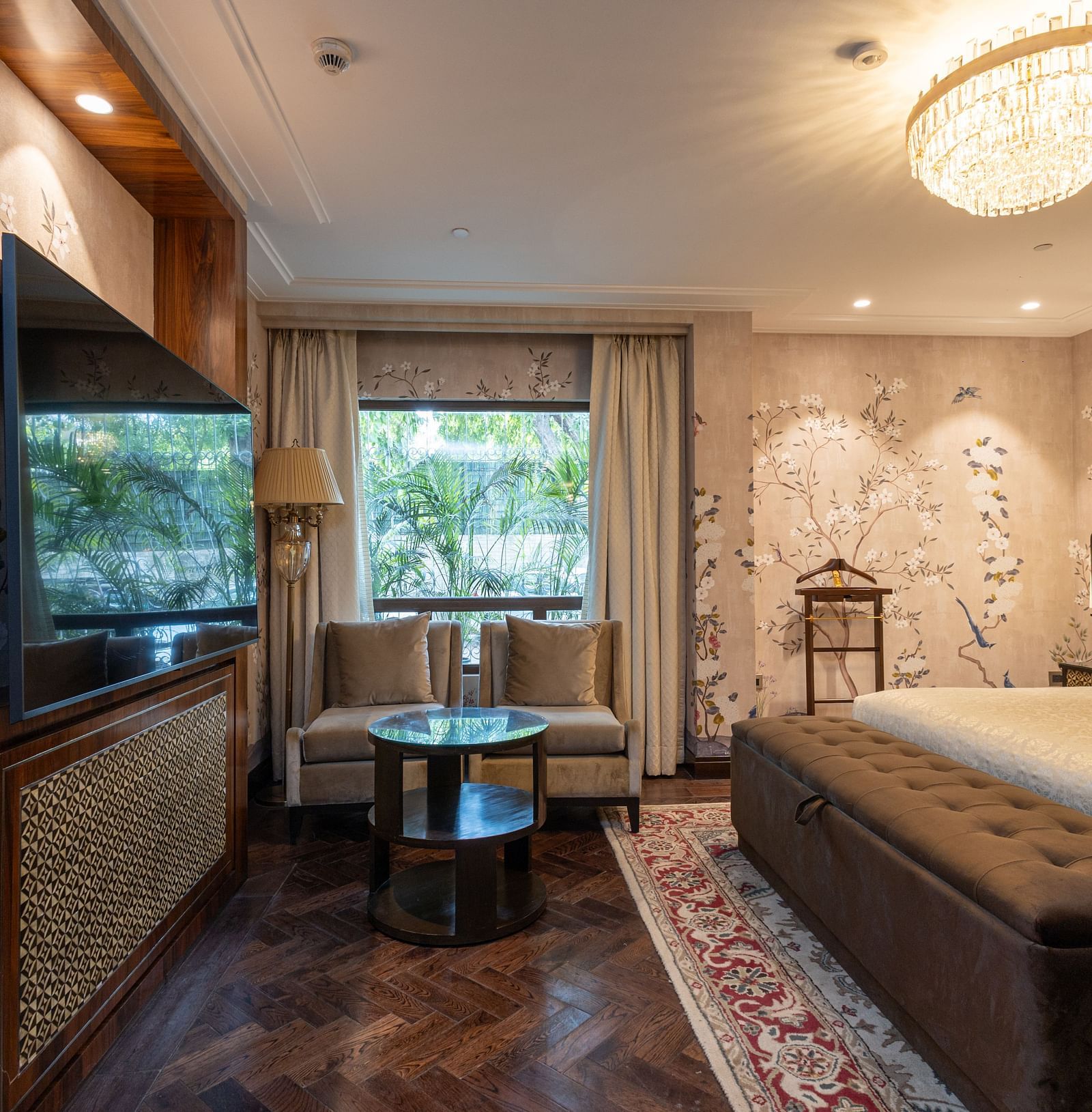 Image of the Cabana Room displaying two single-seater couches and a wall-mounted television - The Claridges New Delhi