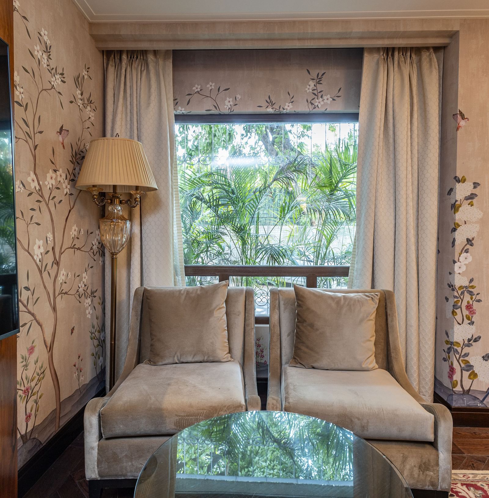 image of two single seater couch seats grey in colour with a huge window behind it at our cabana room - Image of the Cabana Room featuring two single-seater couches and a wall-mounted television - The Claridges New Delhi