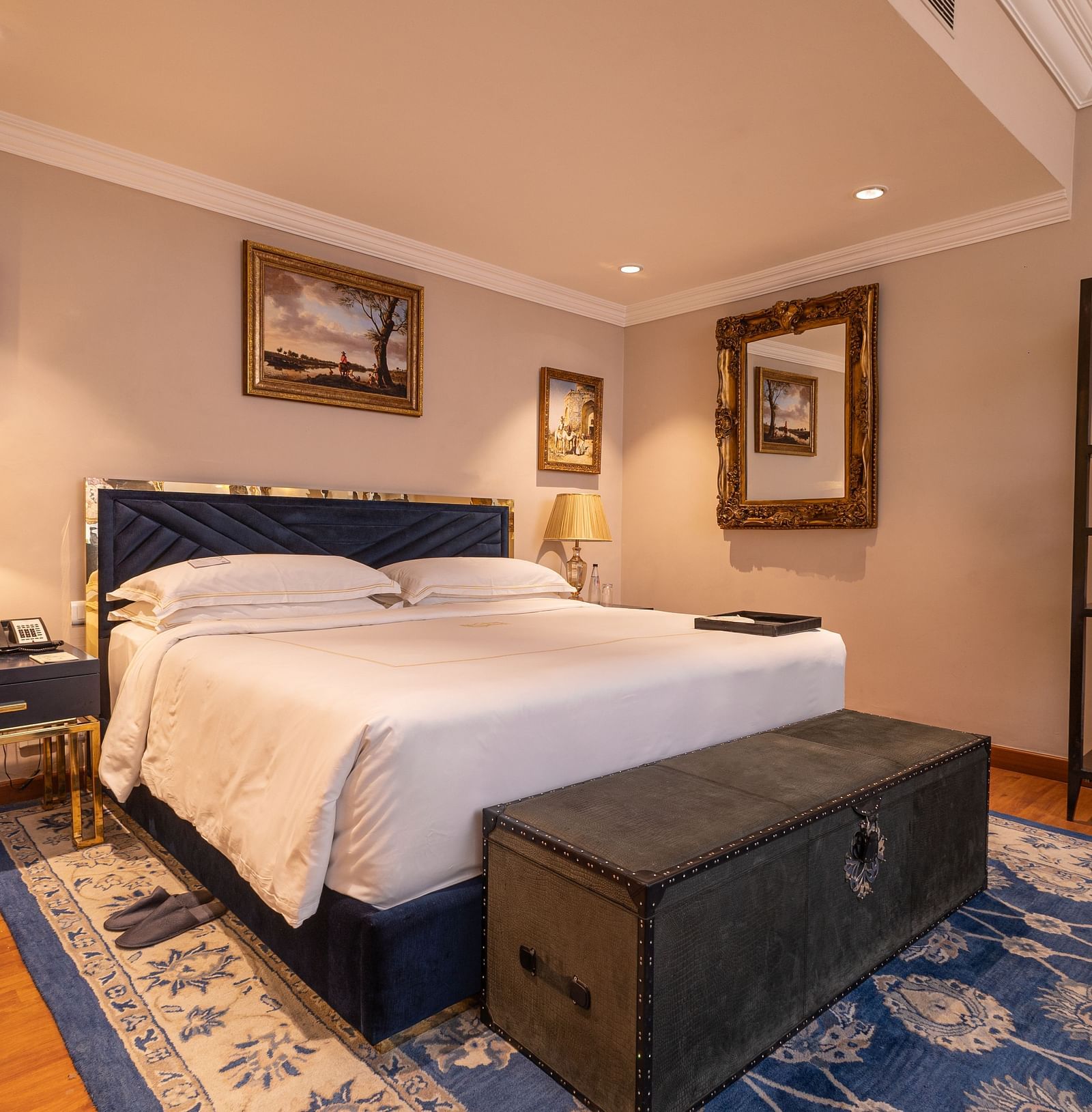 image of the bedroom with a soft comfortable bed with a wooden trunk in front of the bed at our regent suites - The Claridges New Delhi