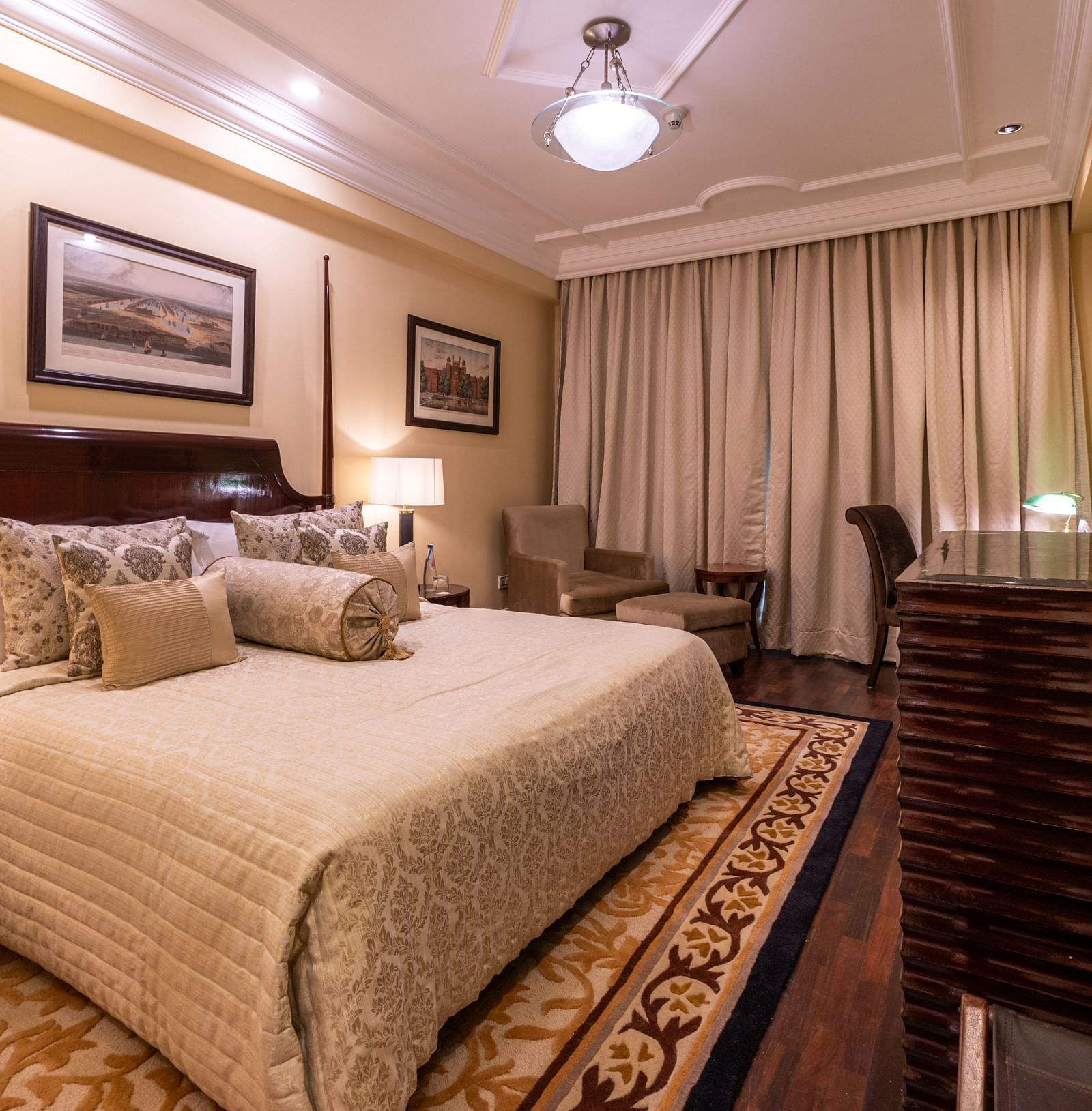image of the bedroom of the heritage parlour room with a king size bed and beautiful photoframes hung on the wall - The Claridges New Delhi