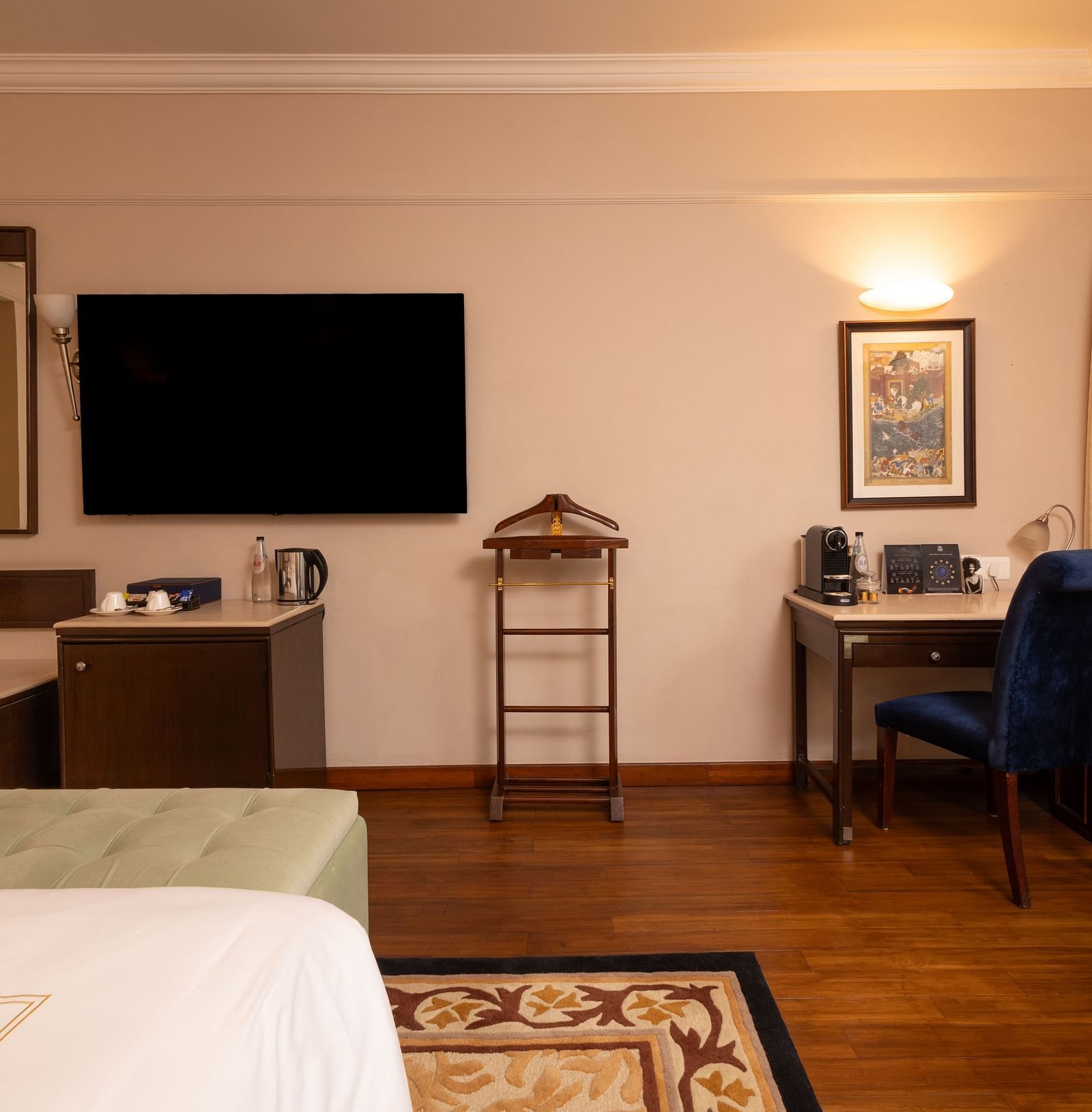 image of the heritage balcony room with a wall mounted tv and a work desk with a blue chair - image of the heritage balcony room with sleek interiors and a a plush king size bed - The Claridges New Delhi