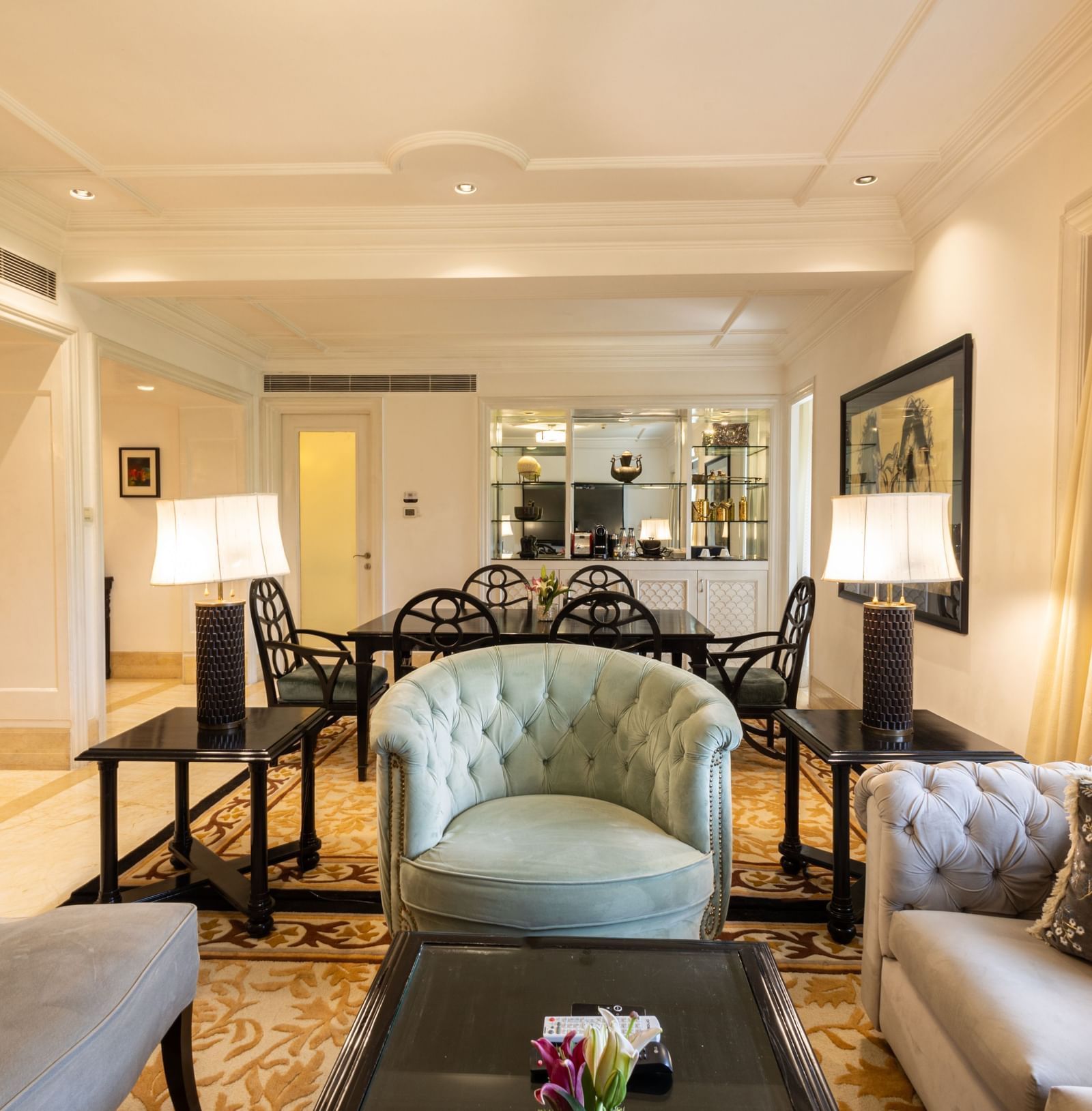 The Claridges New Delhi suite living area has plush seating, a patterned rug, and classic artwork.