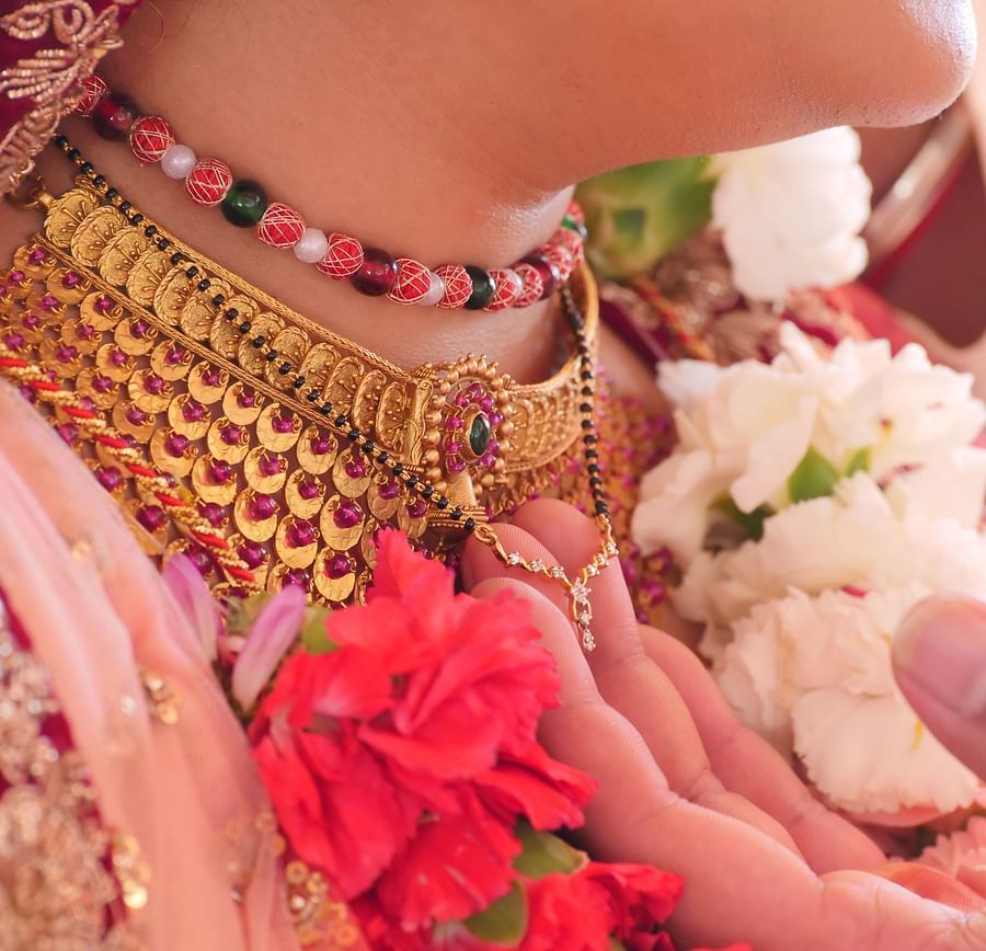 a woman wearing golden ornaments and pink saree