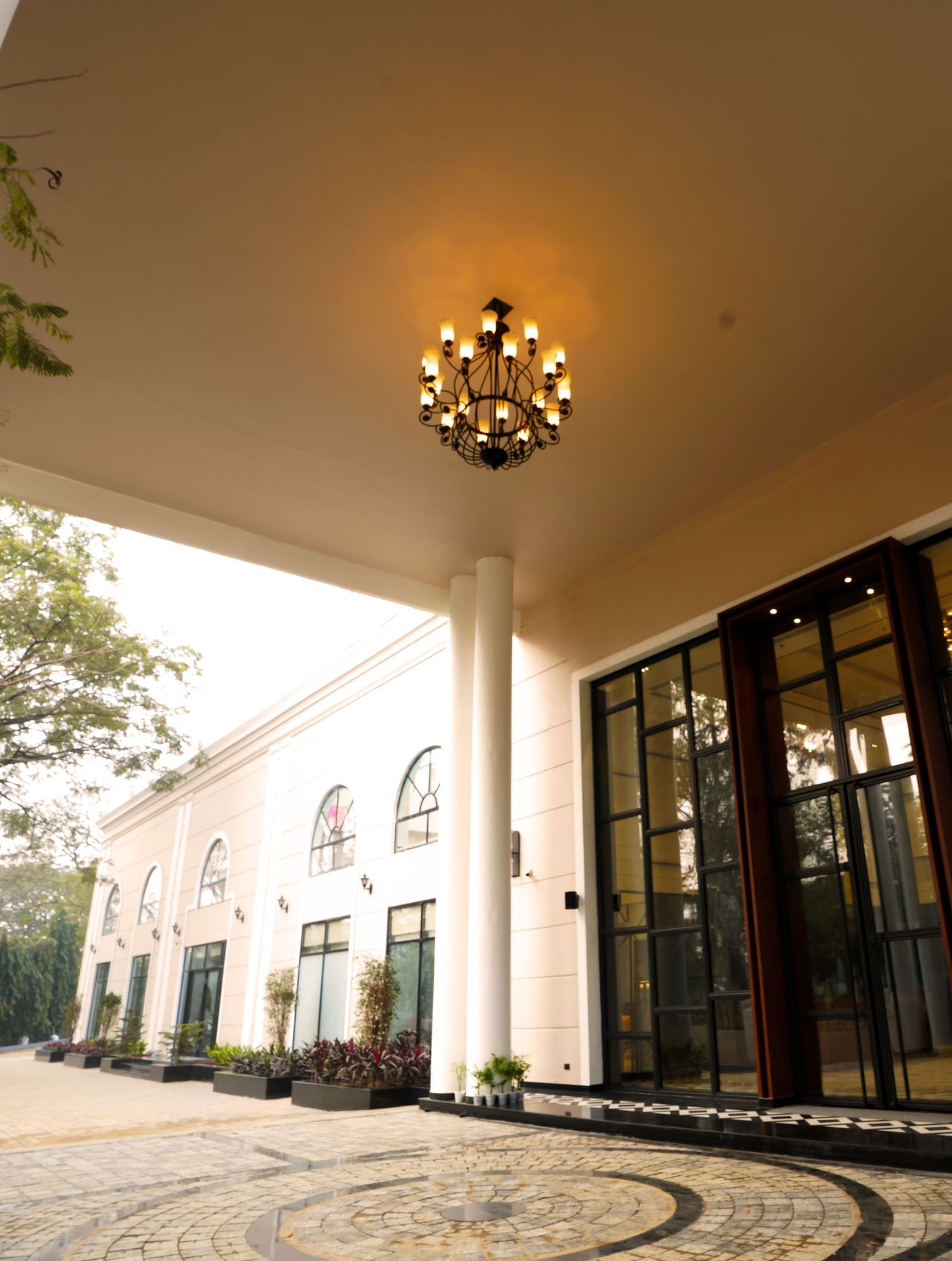 The entrance of Polo Hotel Agartala fetauring a chandelier and a giant floor to glass door.