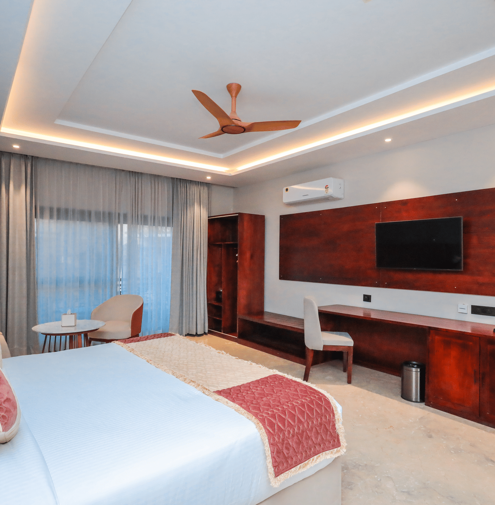 Bedroom with large bed, TV, and desk in modern decor at Ananta Spa and Resorts, Jaipur.