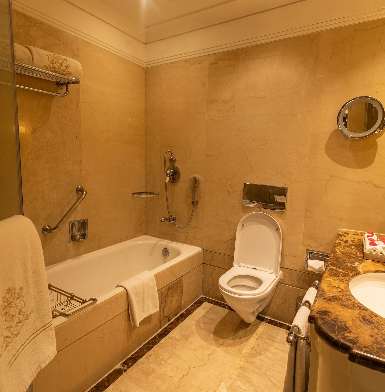 Washroom of the Luxury King Bed Room with Balcony at The Claridges New Delhi, featuring a bathtub, sleek sink, and a wall-mounted lamp in the corner