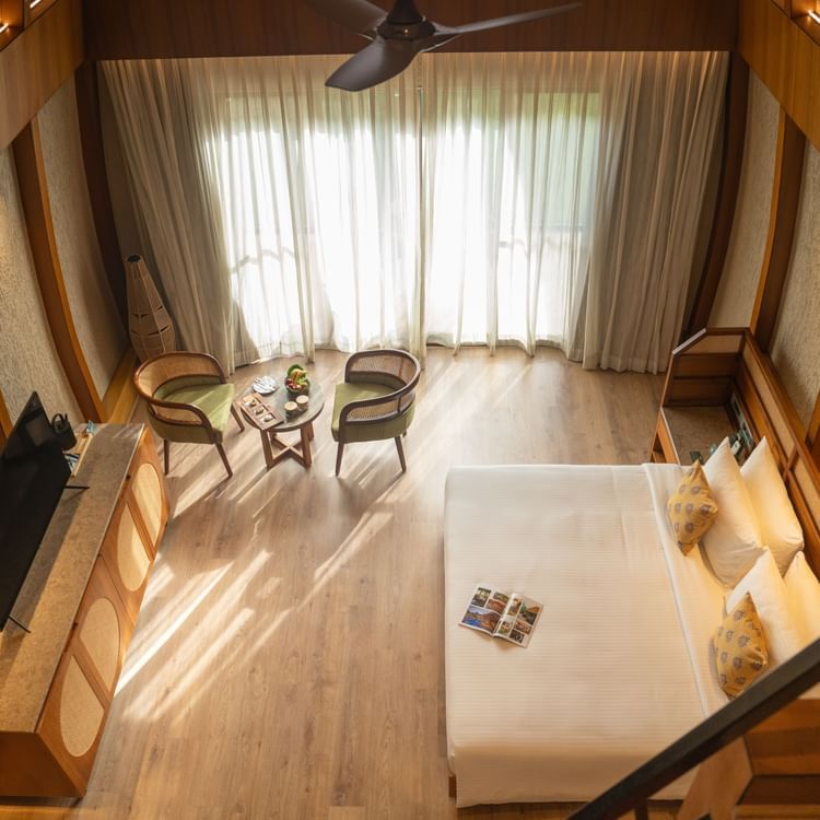 A stunning king size bedroom with high ceilings, seating area, and large windows allowing natural light at Ananta Spa and Resort, Ajabgarh.