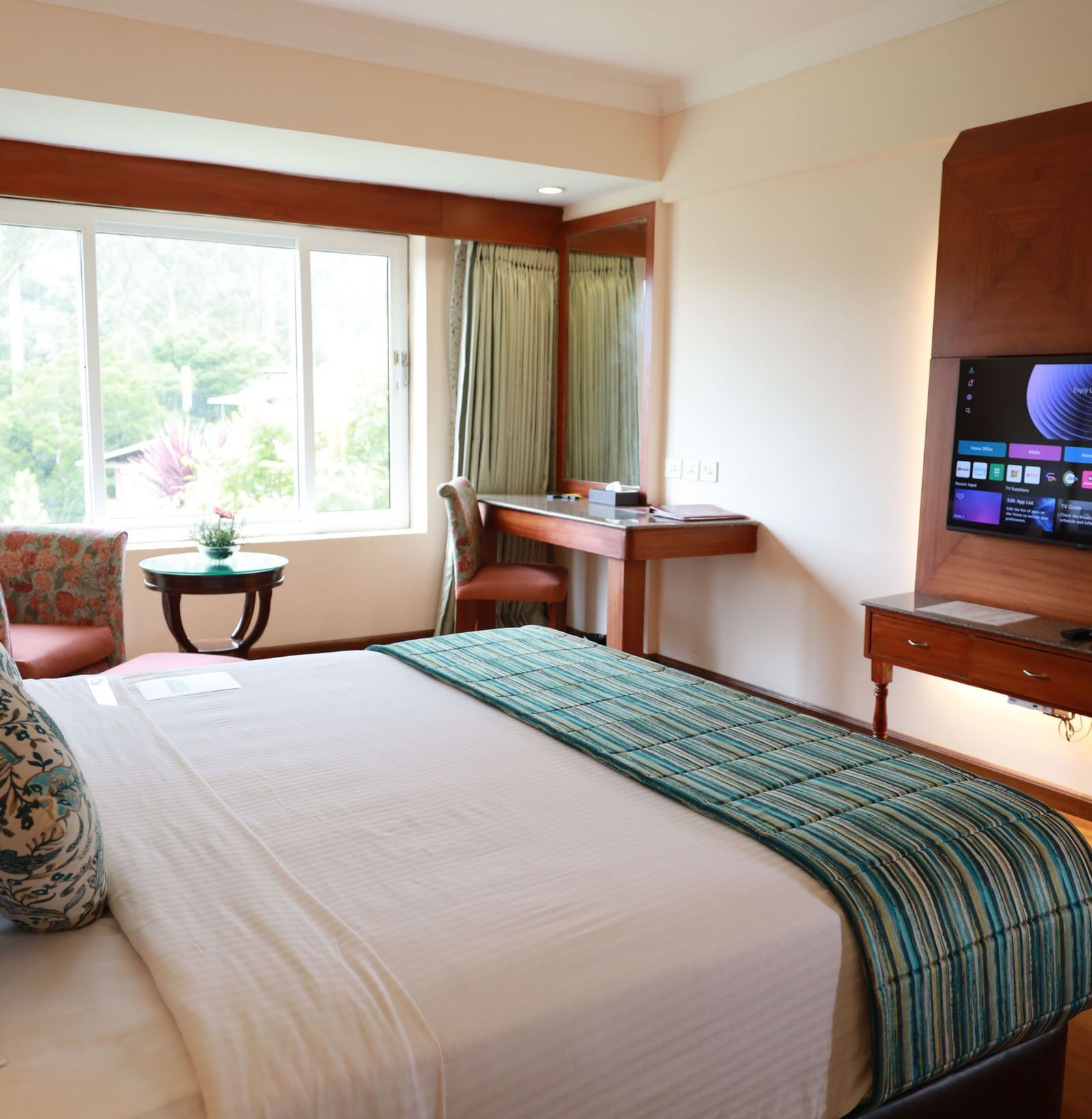 Superior Room at Accord Highland Ooty room, featuring a king-sized bed, a window view, and a wall-mounted TV.