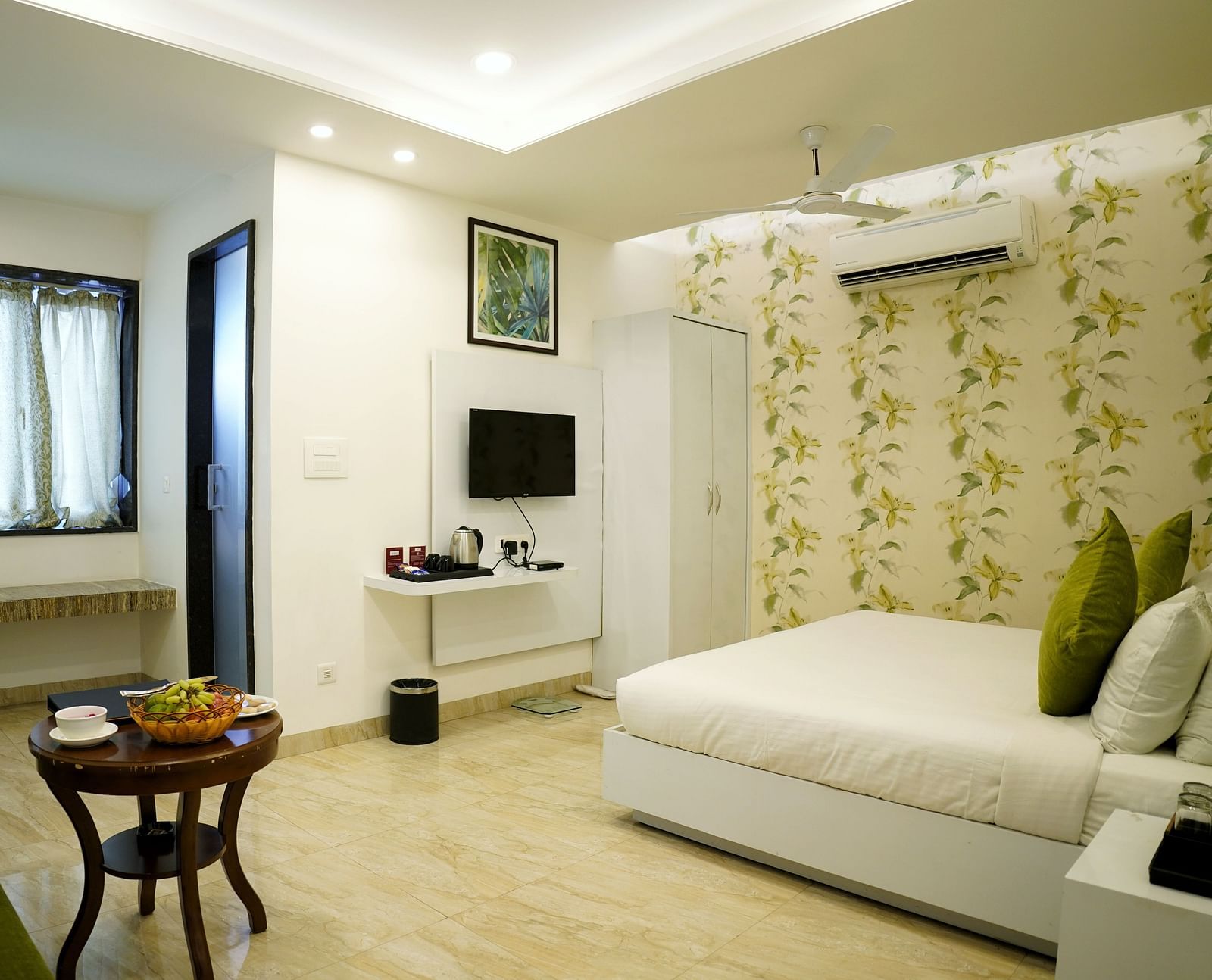 A serene bedroom setup with a large window and a white and green colour scheme - TGI Insignia, Bhopal
