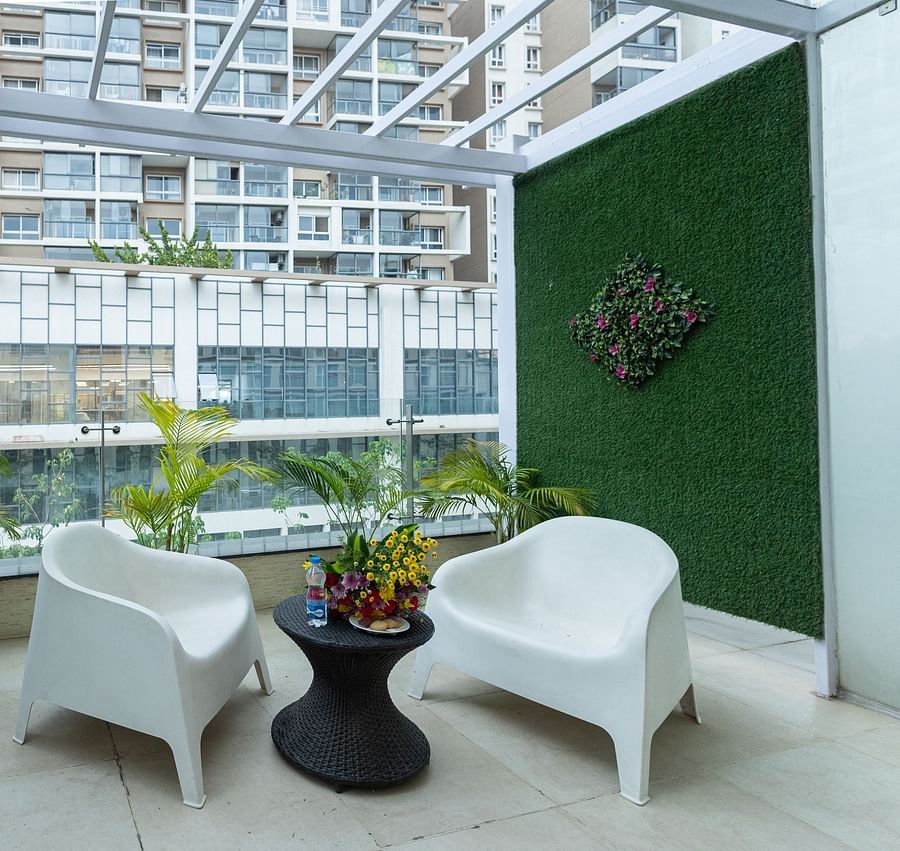 Balcony outside the executive room with two chairs, a table, and a flower bouquet at Icon Premier Hotel by Bhagini, Devarabisanahalli