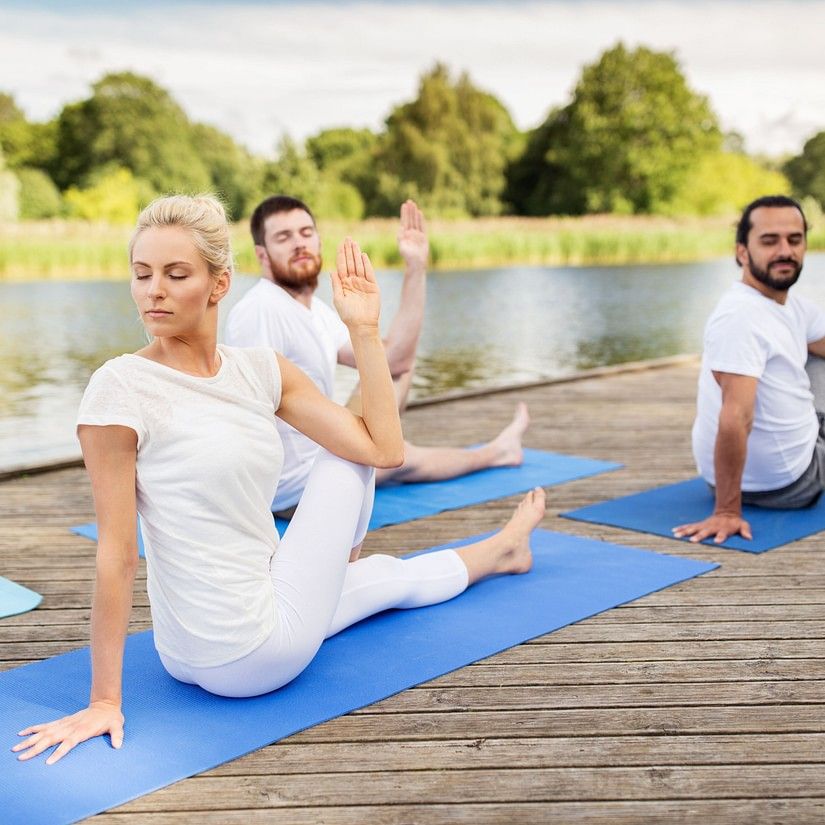 3 people doing yoga by a water body during daytime