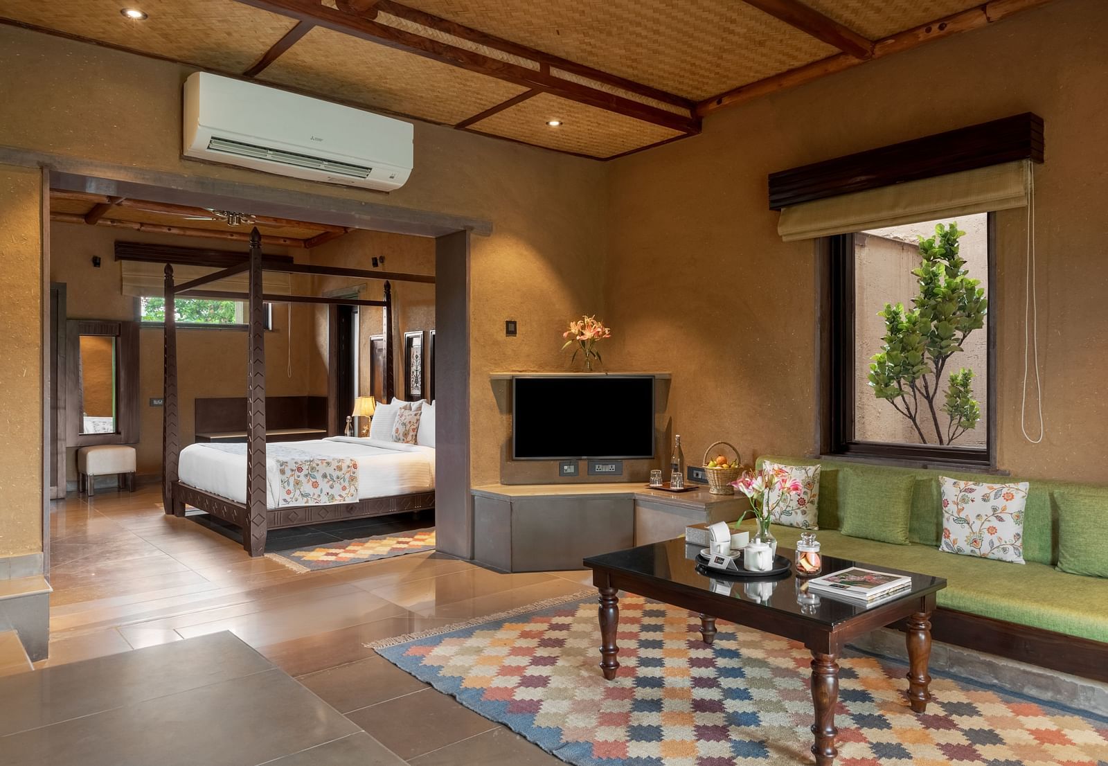 A cosy living area featuring a corner sofa and a dining table at Aamaghati Wildlife Resort.