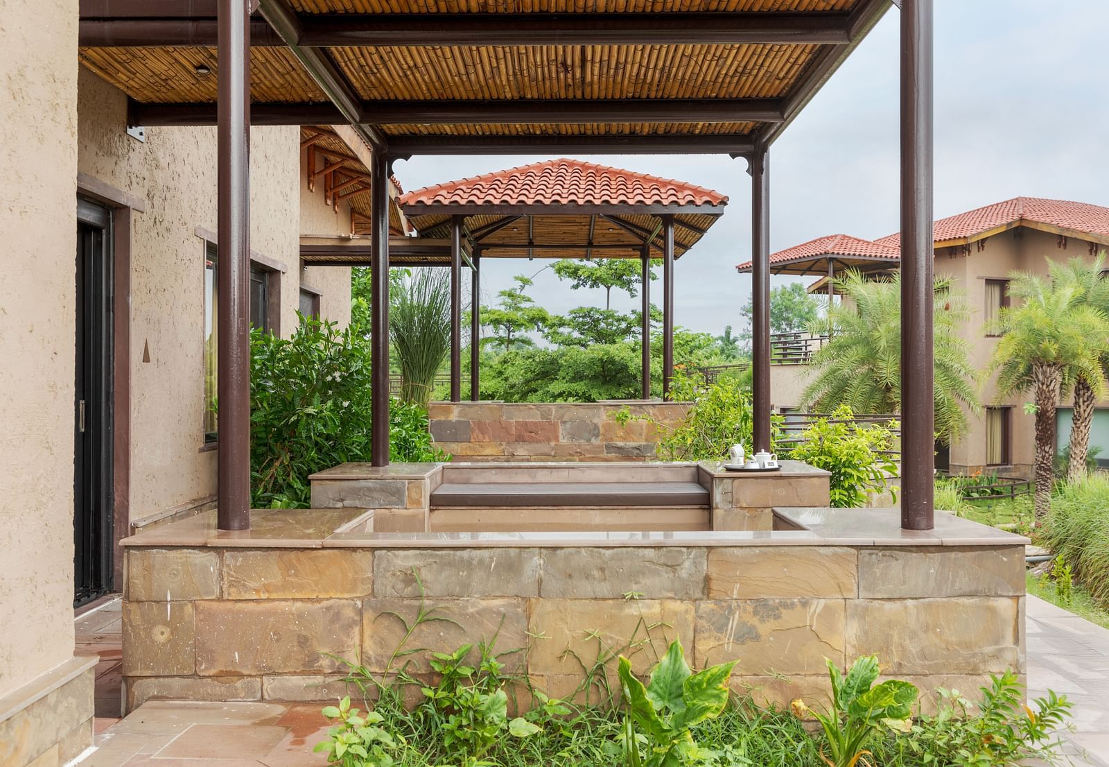 A charming outdoor seating area with a pergola and lush greenery at Aamaghati Wildlife Resort.