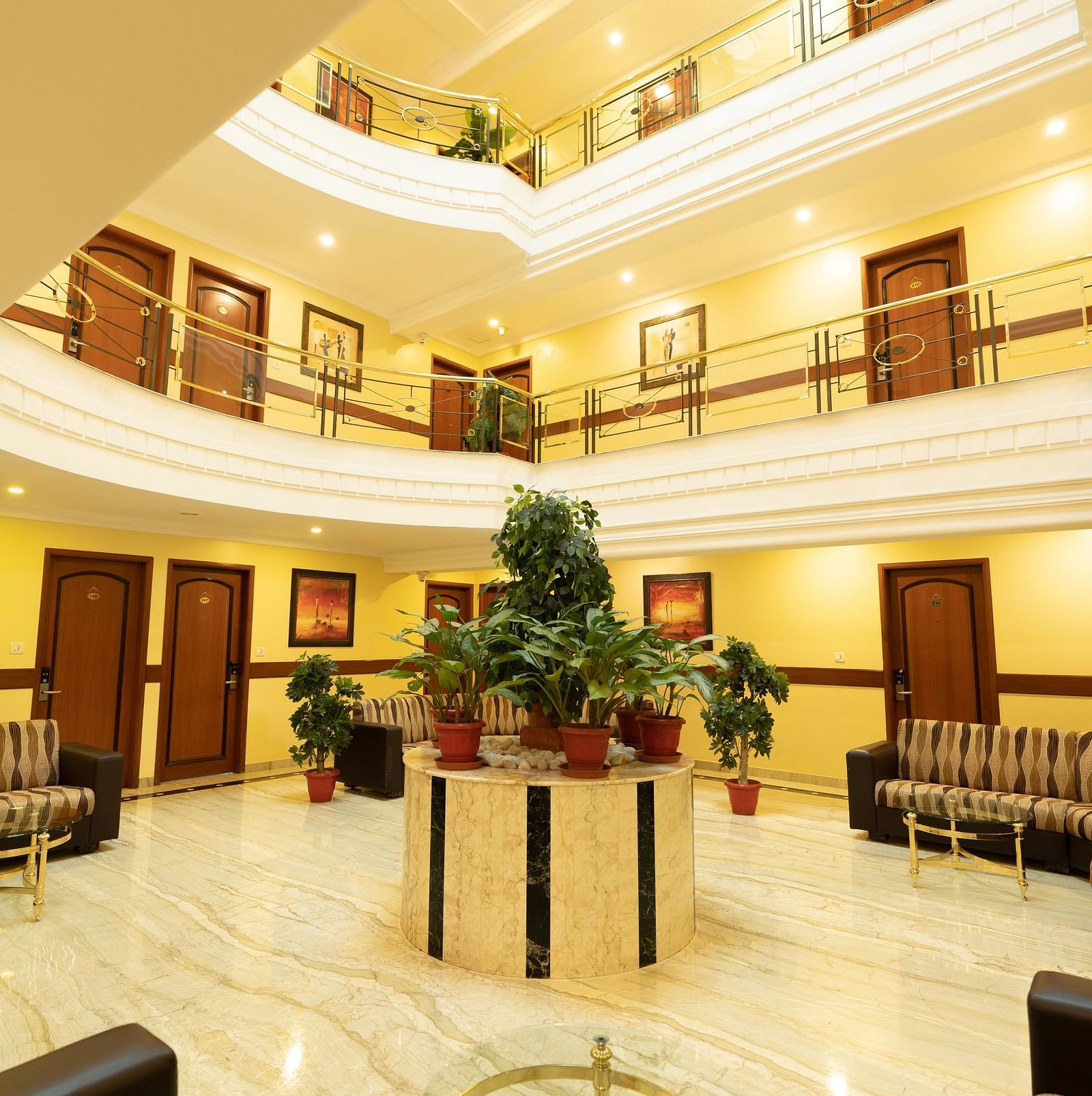 An image of interiors of a multi storey hotel which has a lobby in ground floor with plants  and seating area - Pai Group of Hotels