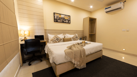 A bedroom with a king size bed, bedside tables, wall art, and  anA/C at Perfectstayz Value Sagar, Amritsar.