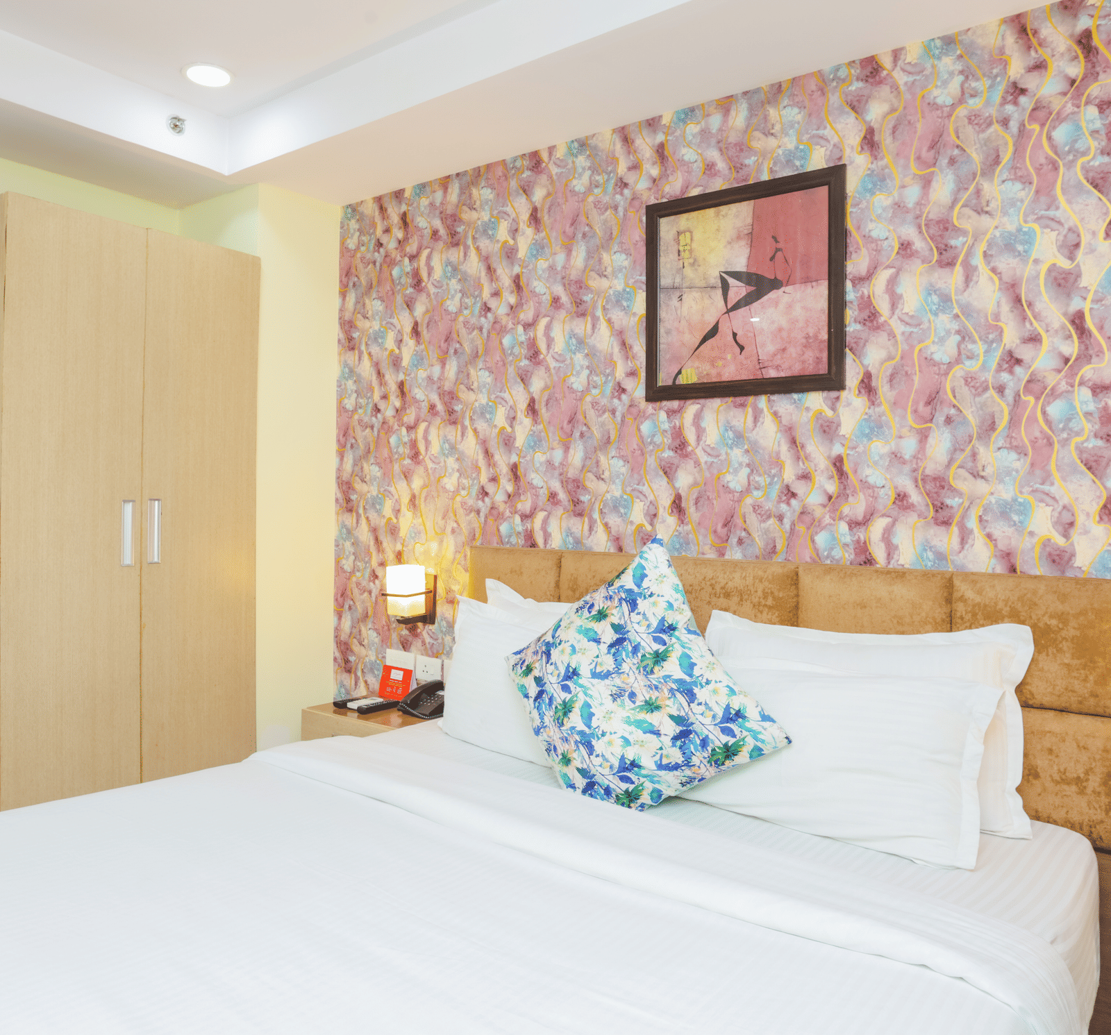 A hotel room with a double bed, patterned wallpaper, and a small minibar area - Hyphen Grand, Haridwar