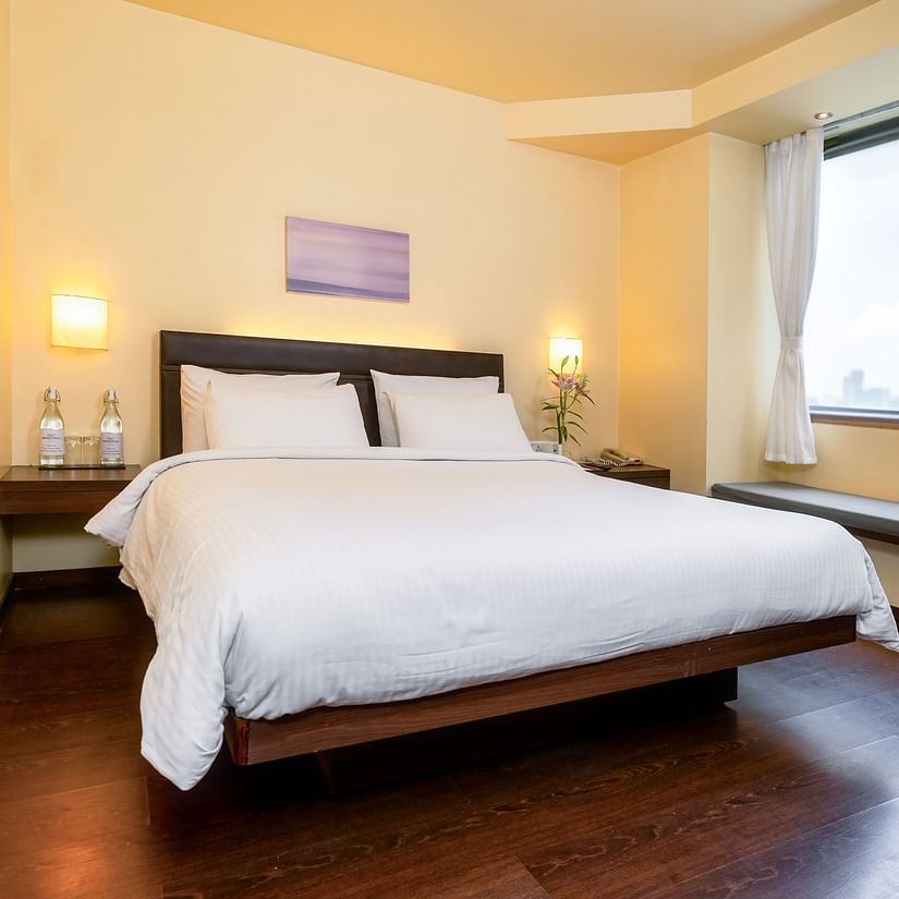 A front view off the suite  with plushy bed and a window with a wall painting  at Marasa Sarovar Portico, Rajkot