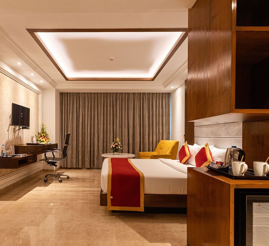 Spacious side view of executive room with a king-size cozy bed and a wall-mounted TV at Icon Premier Hotel by Bhagini, Devarabisanahalli