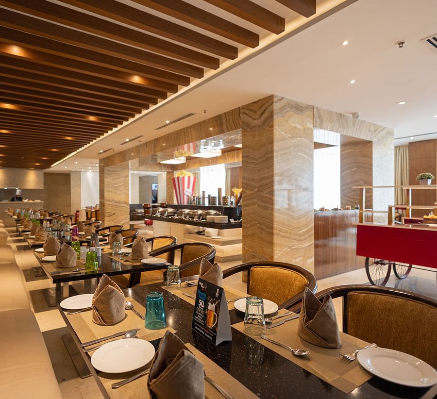 Restaurant with a chaat section on a small wheel and seating arrangements in the corner at Icon Premier Hotel by Bhagini, Devarabisanahalli