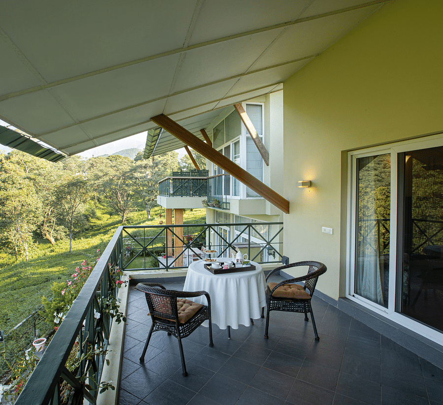A private sit-out area in a balcony with a tea table and chairs outside a room facing the tea gardens and mountain - Lamrin Norwood Green, Palampur