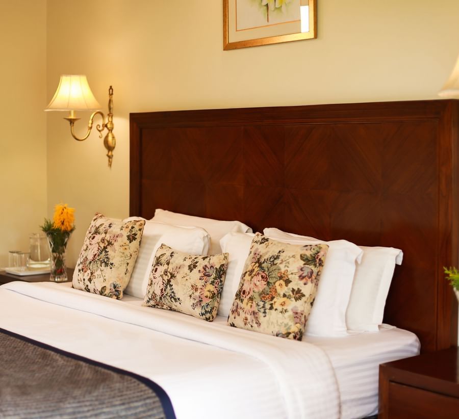 Closer view of a beautifully tucked bed with soft lines and pillows along with bedside lamps - Lamrin Norwood Green, Palampur
