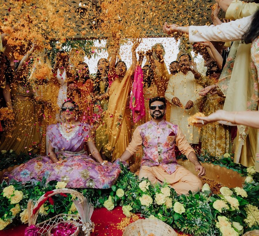 Traditional wedding ritual in progress with the bride seated under a marigold canopy surrounded by family.