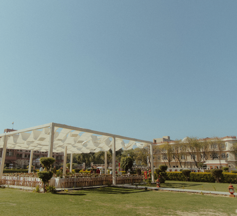 A bright daytime shot of an expansive outdoor event lawn featuring a large white pavilion structure at Umaid Palace.