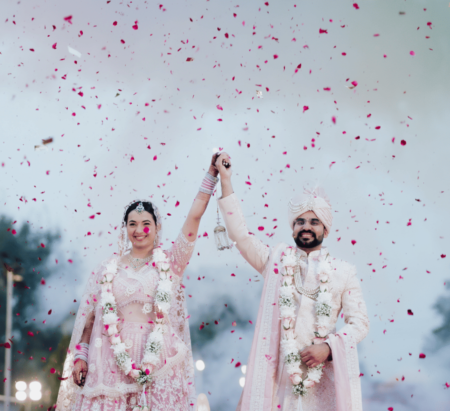 Bride and groom celebrating with confetti during a wedding ceremony at Umaid Palace.
