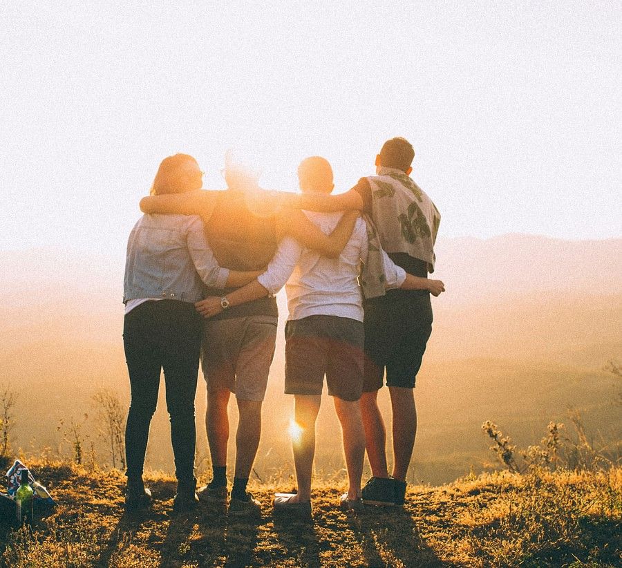 Four friends standing on a hill, silhouetted against a setting sun.