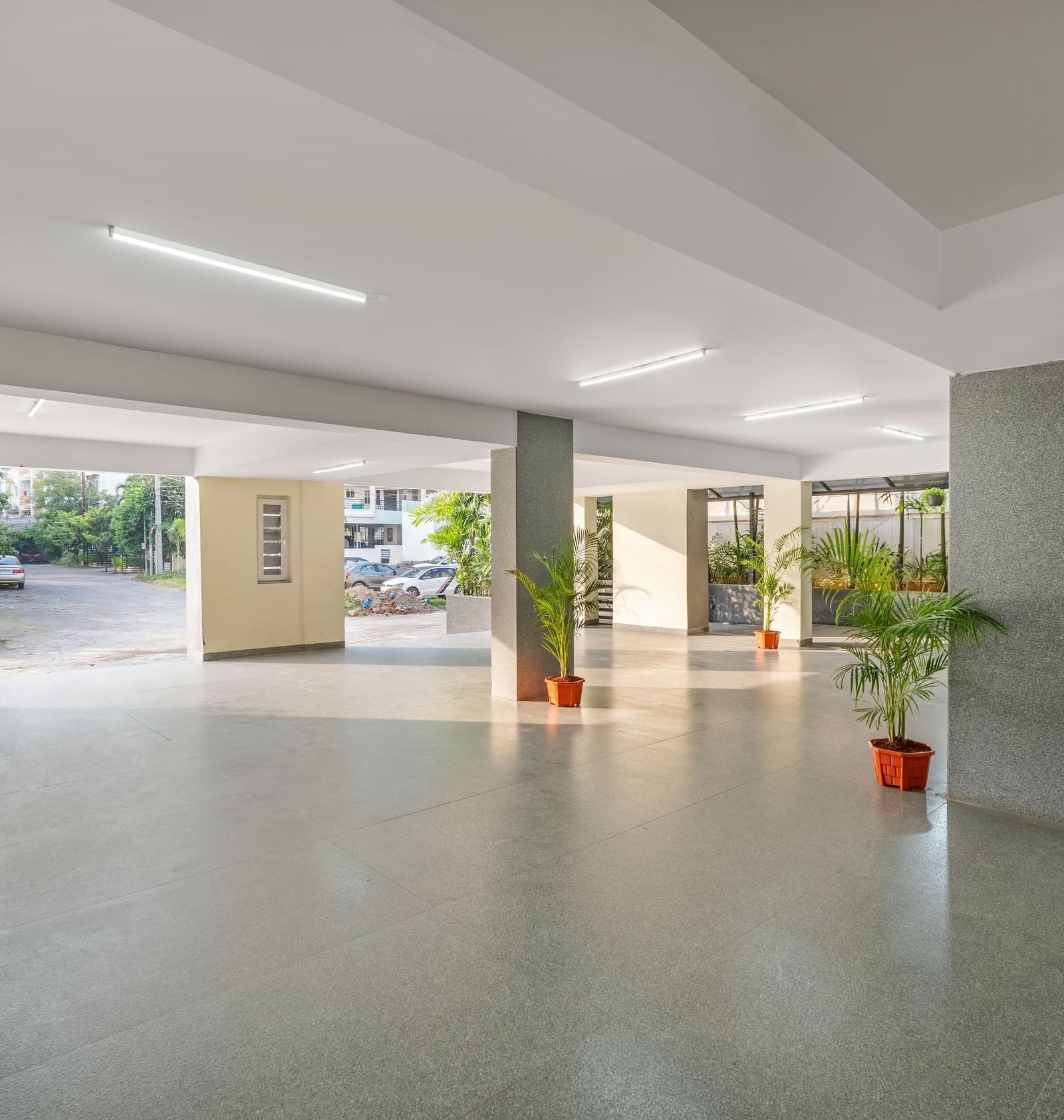 A brightly lit hotel parking area at Destino by Monday Hotels, Gachibowli, with polished floors and potted plants.