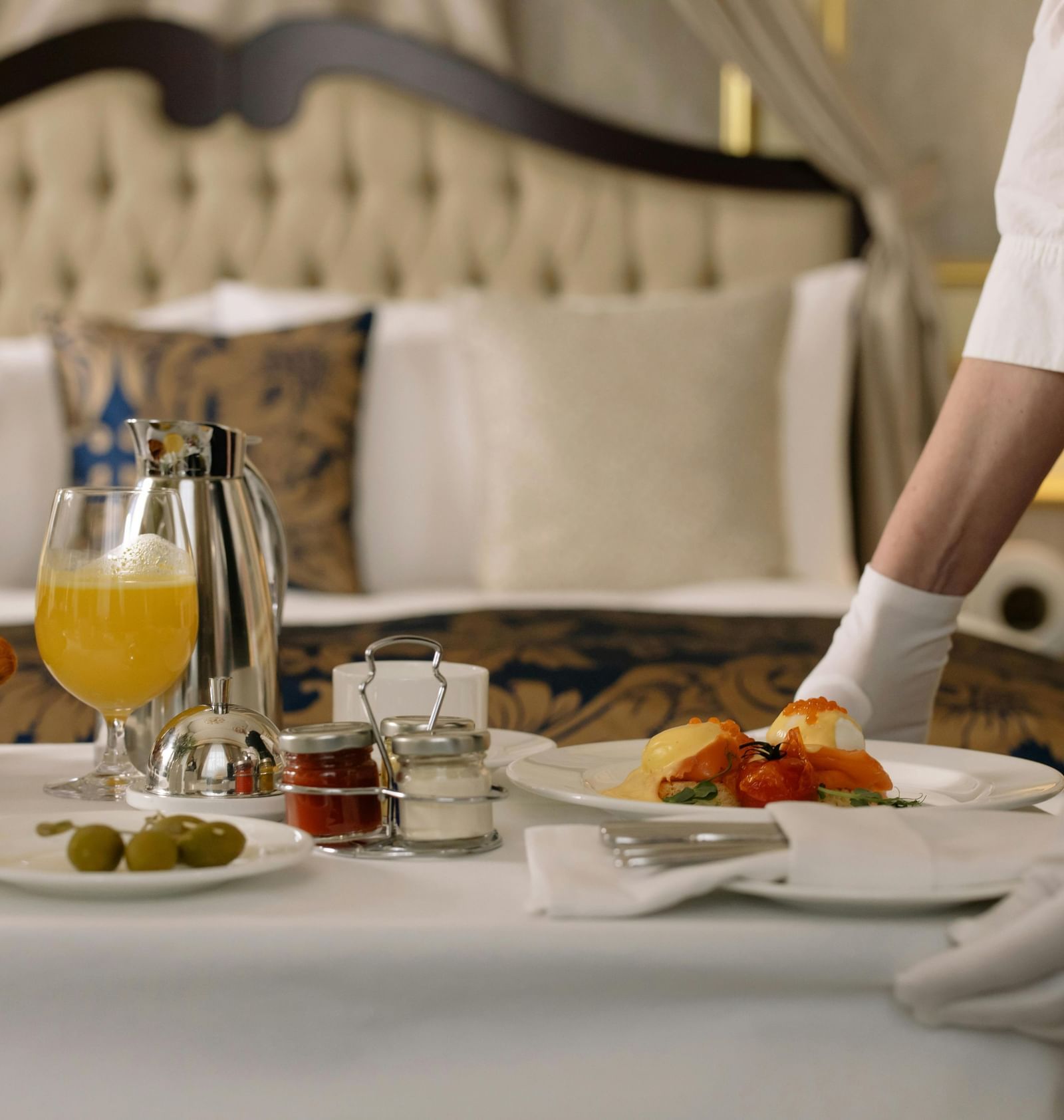 Room service with a well set dining table offering breakfast with juice water and fresh dishes.