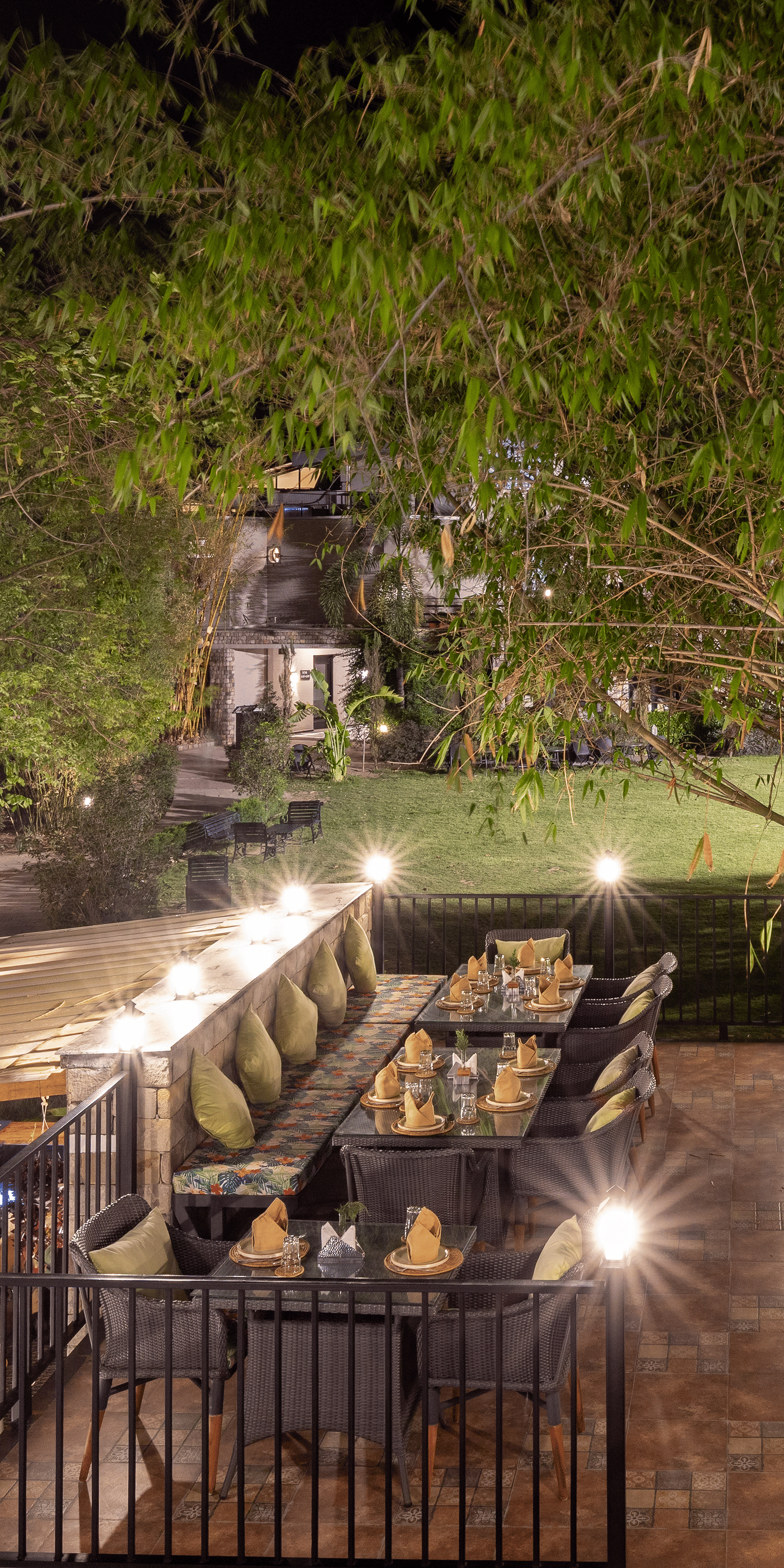 A dimly lit outdoor dining setting at night, with multiple tables illuminated by warm lights at The Golden Tusk, Jim Corbett