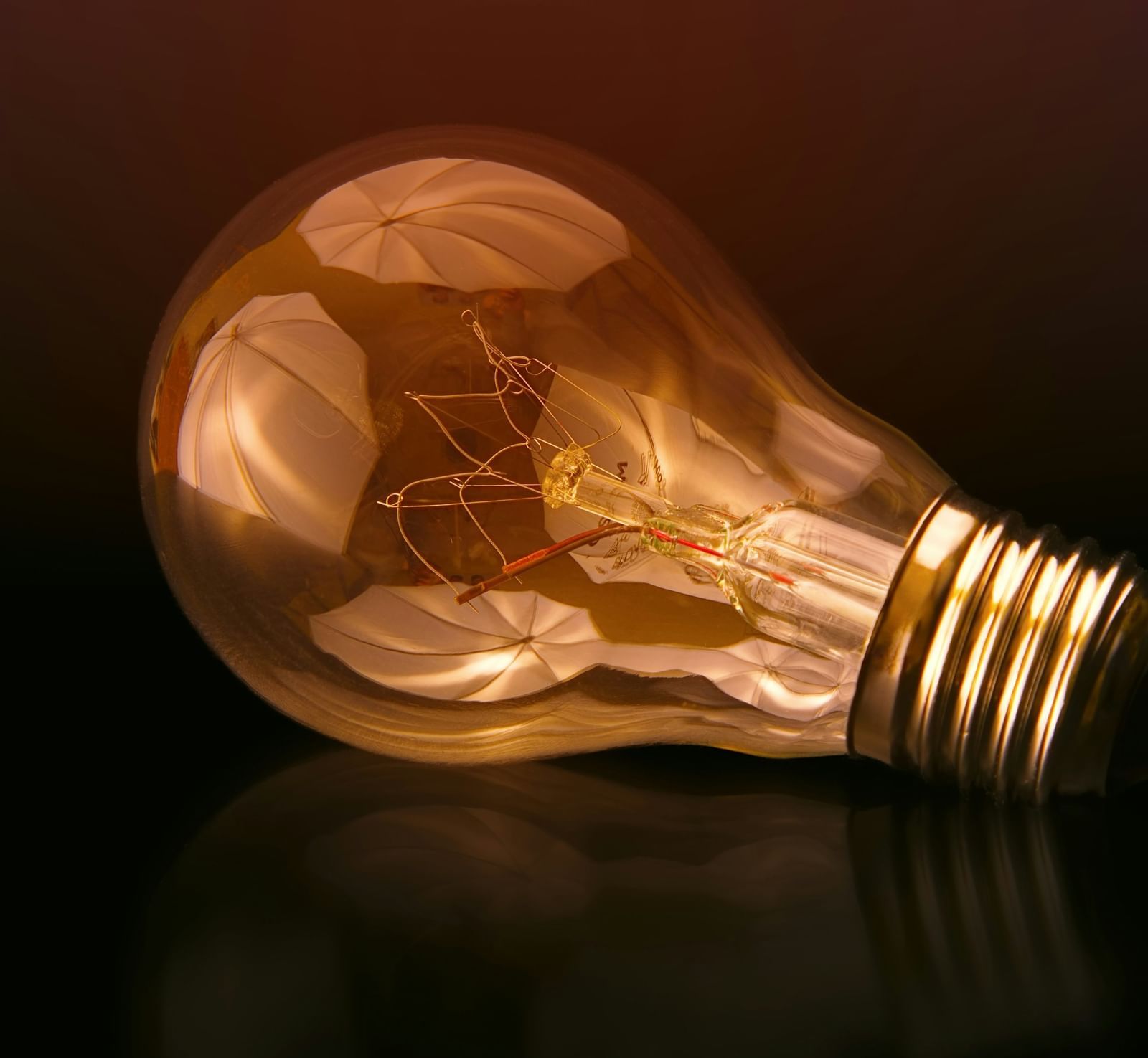 A close-up shot of a filament bulb lying down on a black surface.