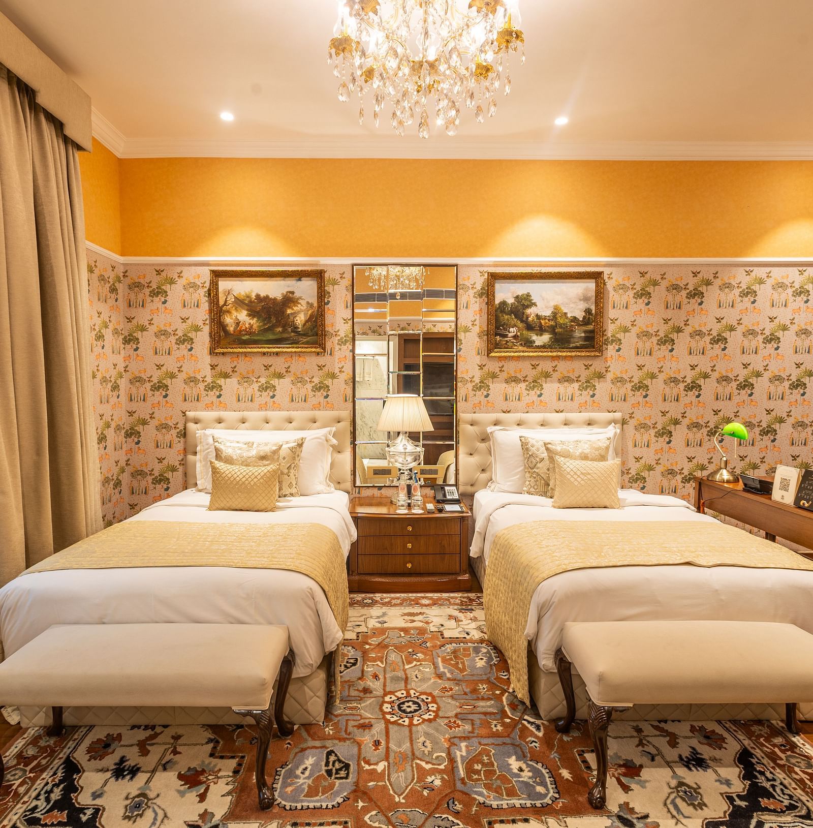 Grand Luxury Twin Bed Room at The Claridges New Delhi, featuring twin beds with a mirror between them and an elegant chandelier hanging overhead