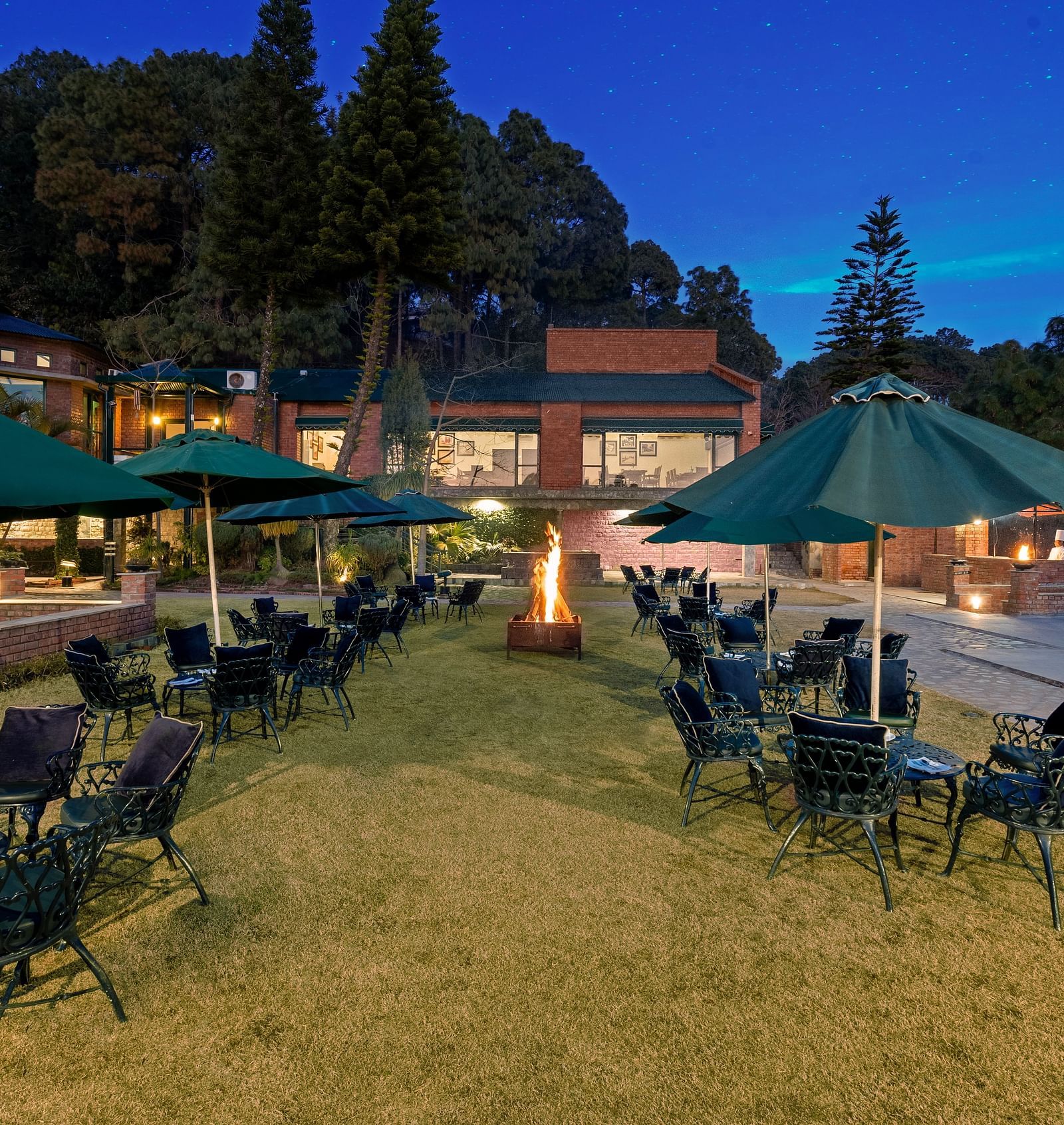 Outdoor Bonfire at Baikunth resort, kasauli with arranged chairs under the umberalla. 